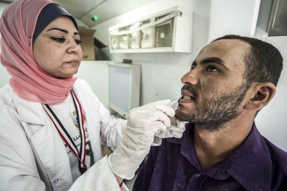 An Egyptian medical staffer takes oral samples from a labourer undergoing examination for hepatitis C at the construction site of Egypt’s new “administrative capital” in Cairo. Photo AFP