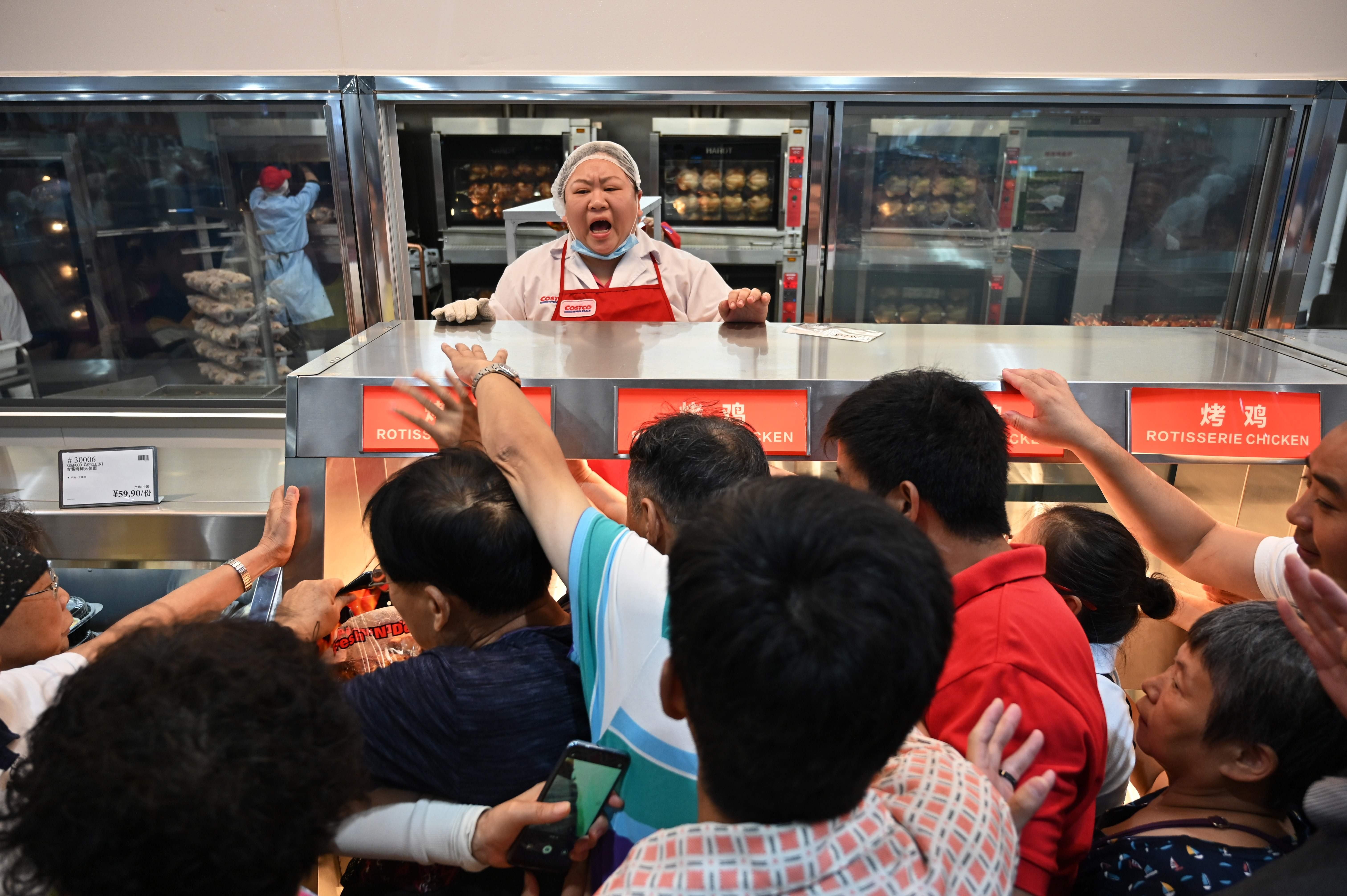 People try to buy a roast chicken at a Costco store in Shanghai, the first in China, on its opening day on August 27. Consumers in both the US and China would benefit from a reduction of trade frictions between the two countries. Photo: AFP
