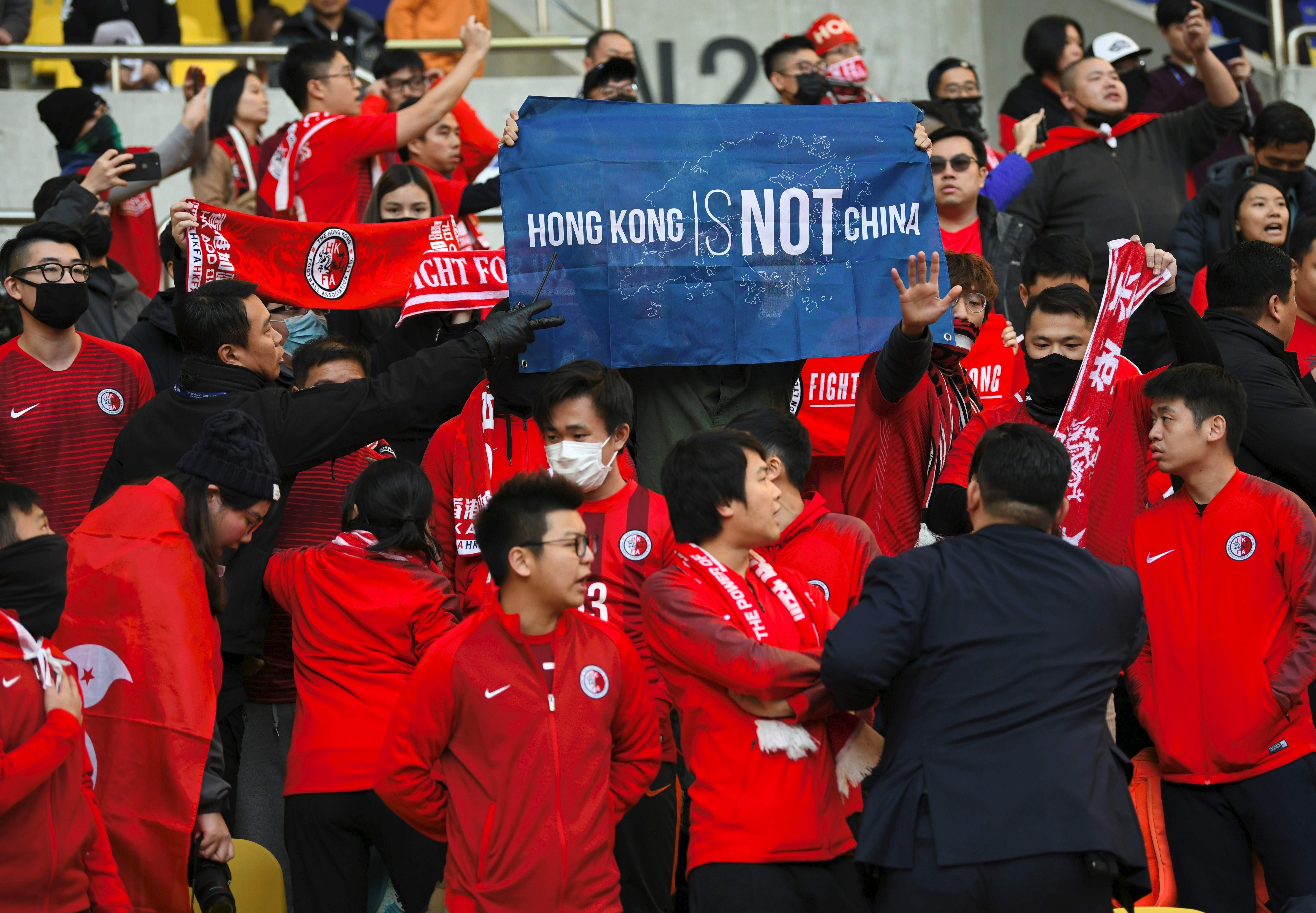 Hong Kong supporters hold a banner reading “Hong Kong is not China" as security members try to take it away match between Hong Kong and China in Busan. Photo: AFP