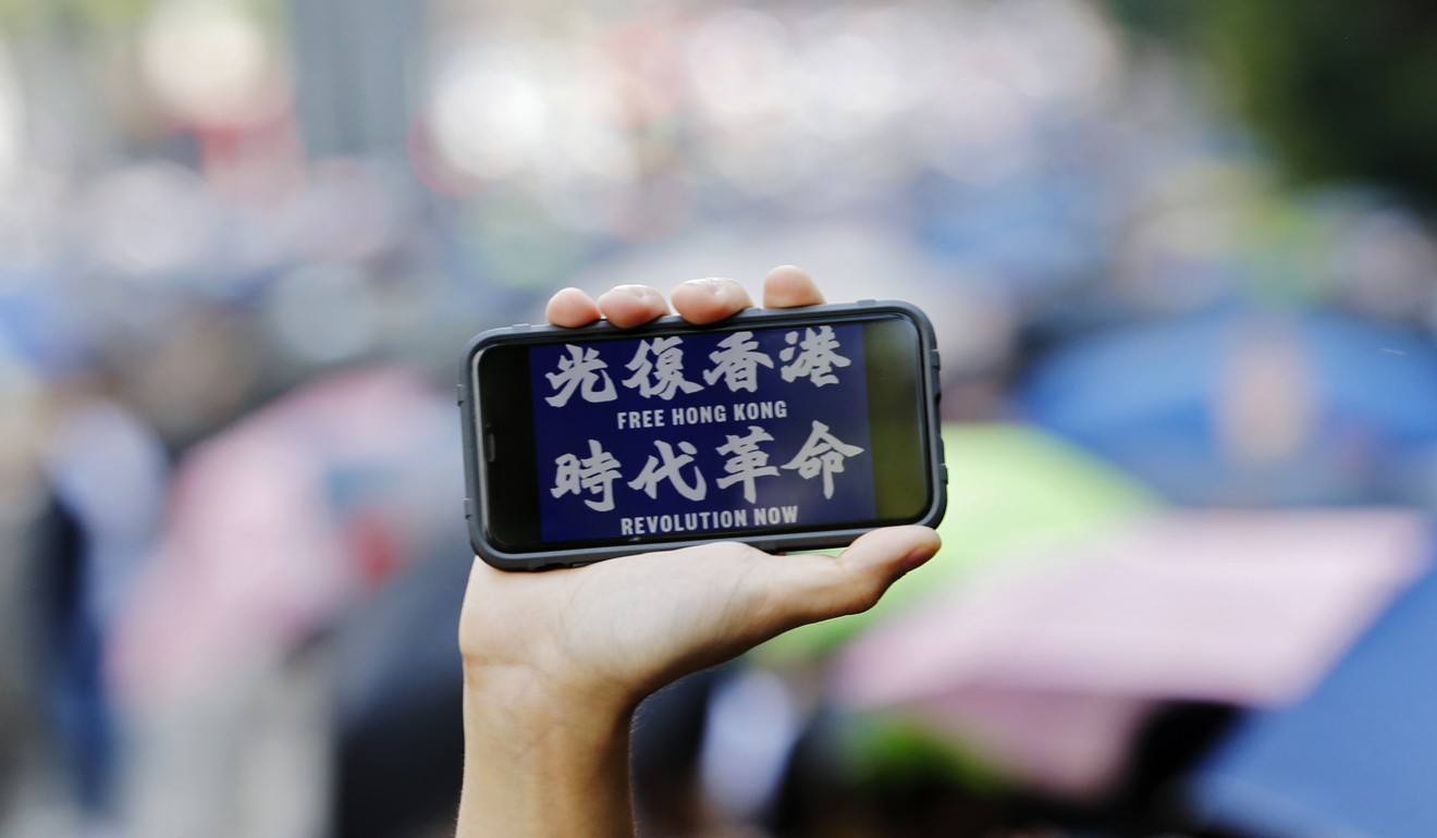 A protester in Hong Kong holds up a mobile phone. Photo: EPA