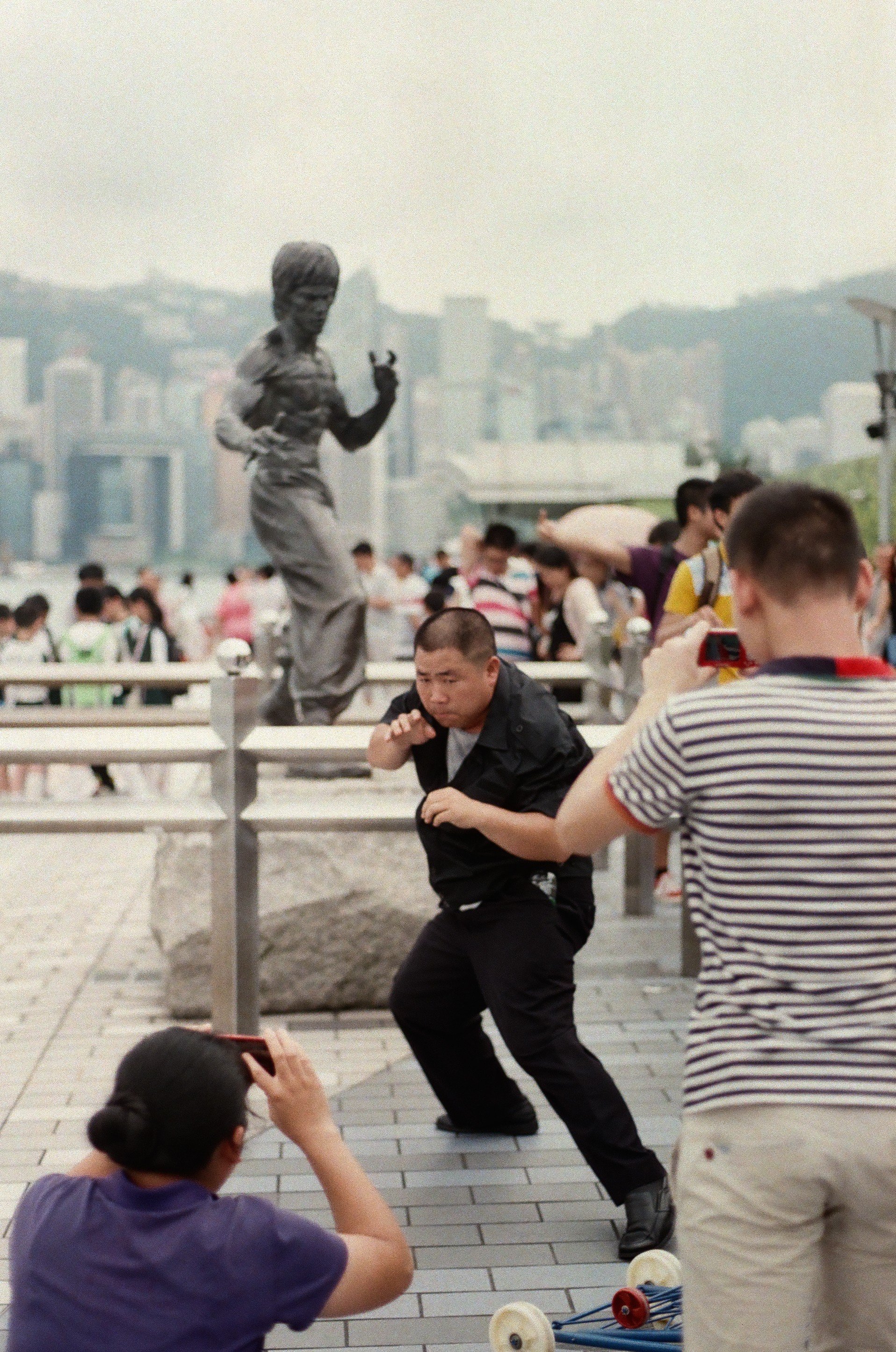 A man posing in front of a statue of Bruce Lee in Tsim Sha Tsui, Hong Kong.
