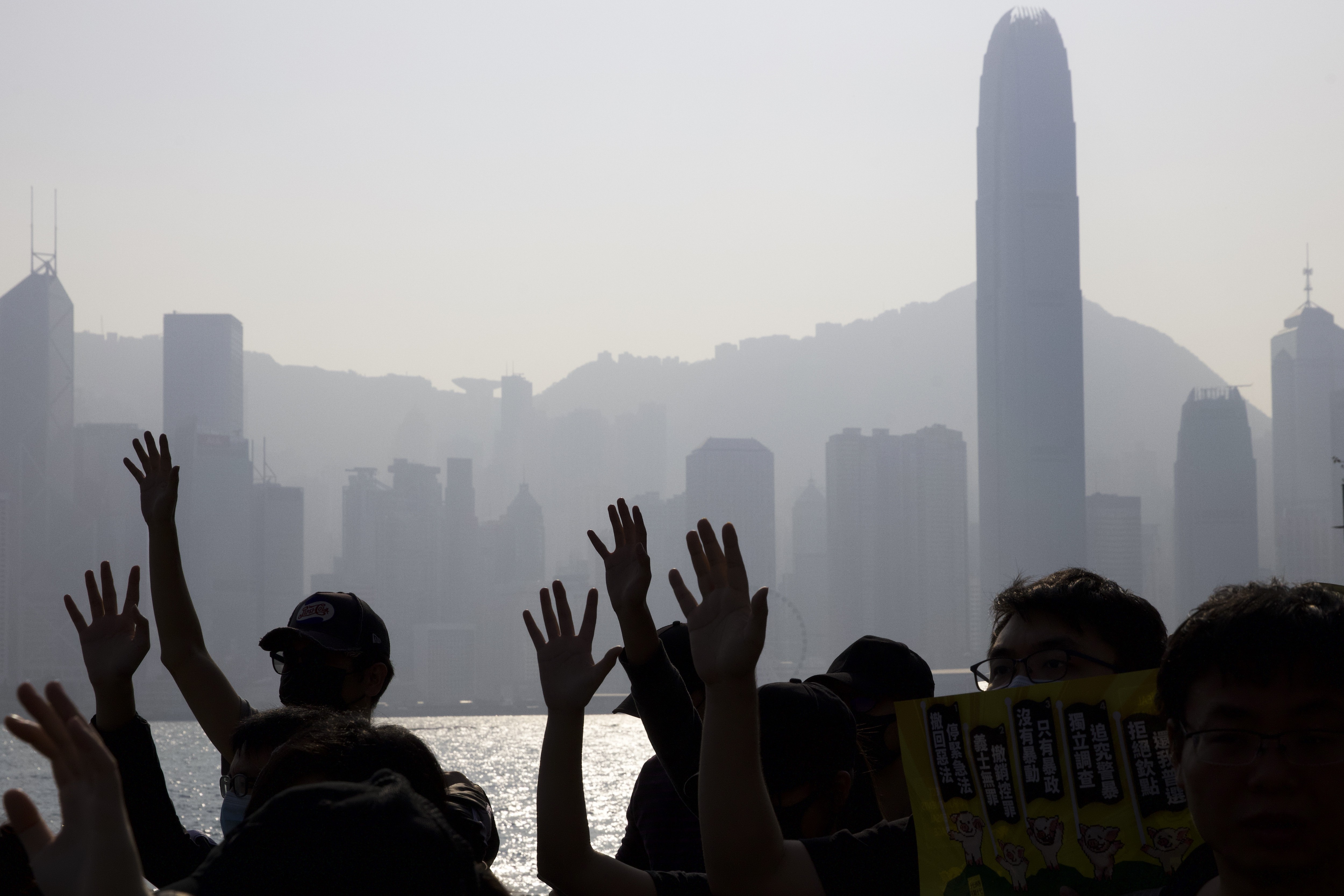 Protesters raising their hands to symbolise their five demands are silhouetted against the iconic Hong Kong skyline during a march on December 1. Photo: AP