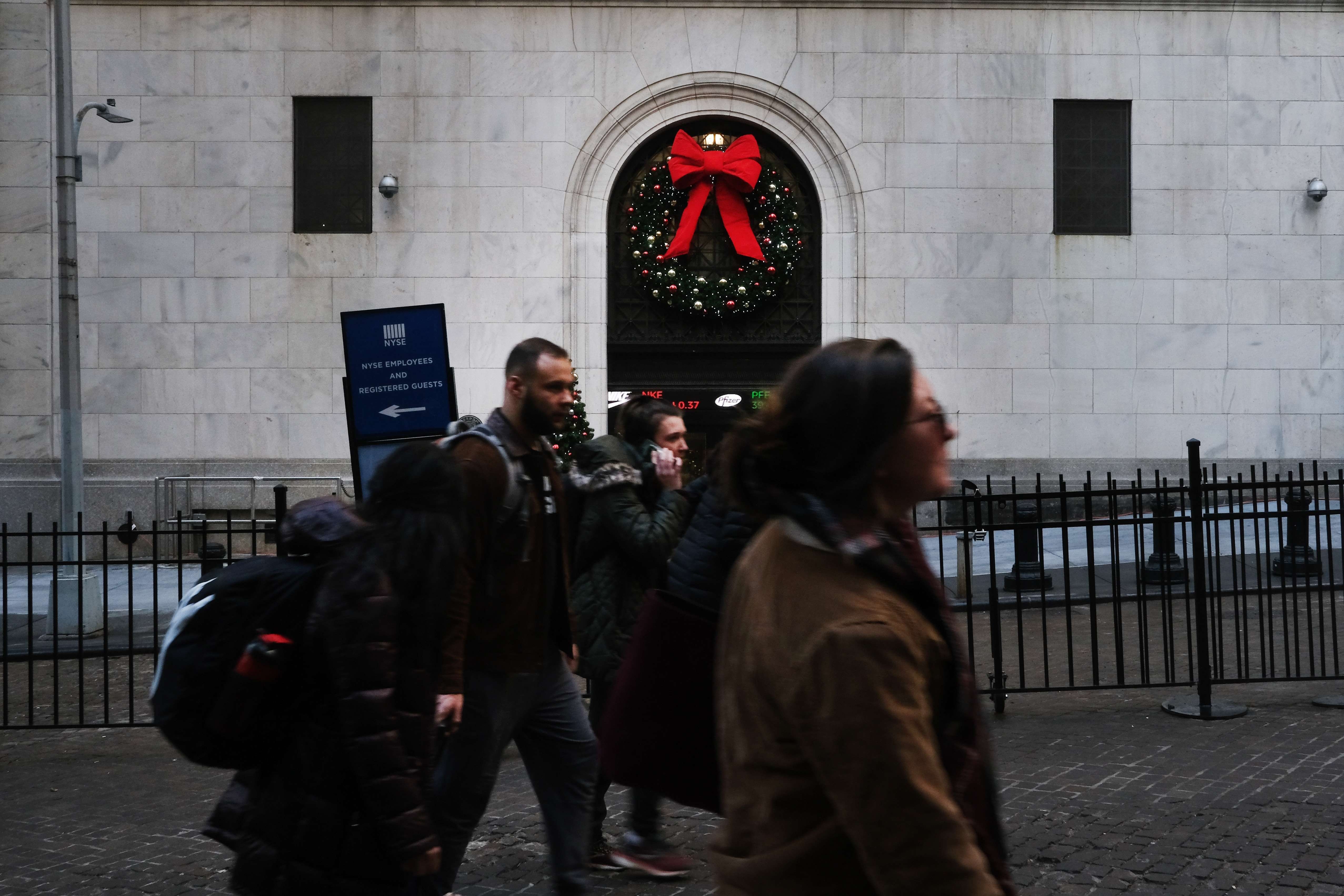 People walk by the New York Stock Exchange at the beginning of the Christmas holiday week on December 23. Aggressive monetary policy easing by central banks around the world over the past year had a huge impact on asset returns, squeezing up valuations on stocks, credit and bonds alike. Photo: Getty Images / AFP