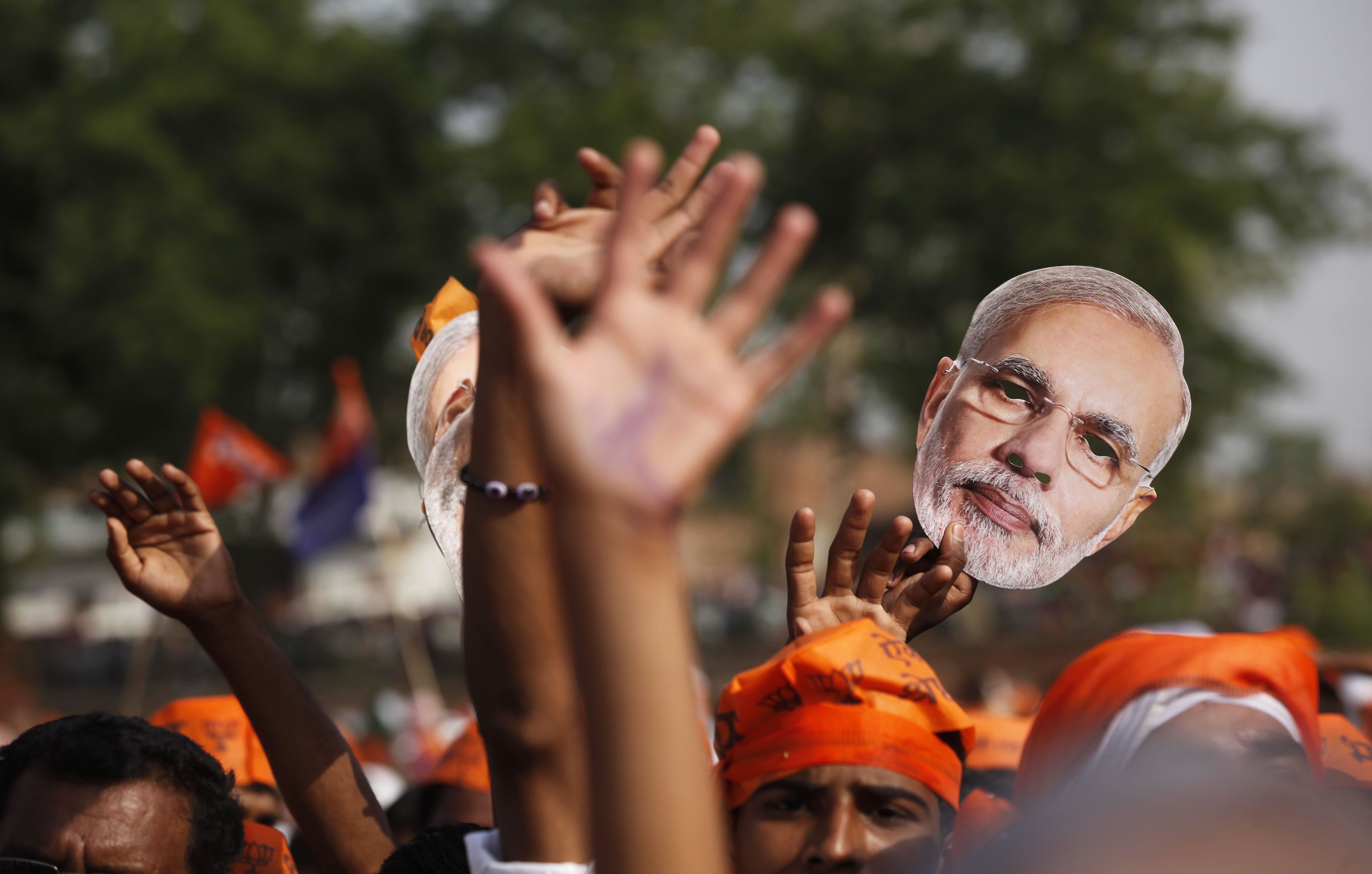 A supporter of India’s Hindu nationalist Bharatiya Janata Party holds up a mask of Prime Minister Narendra Modi. Photo: AP