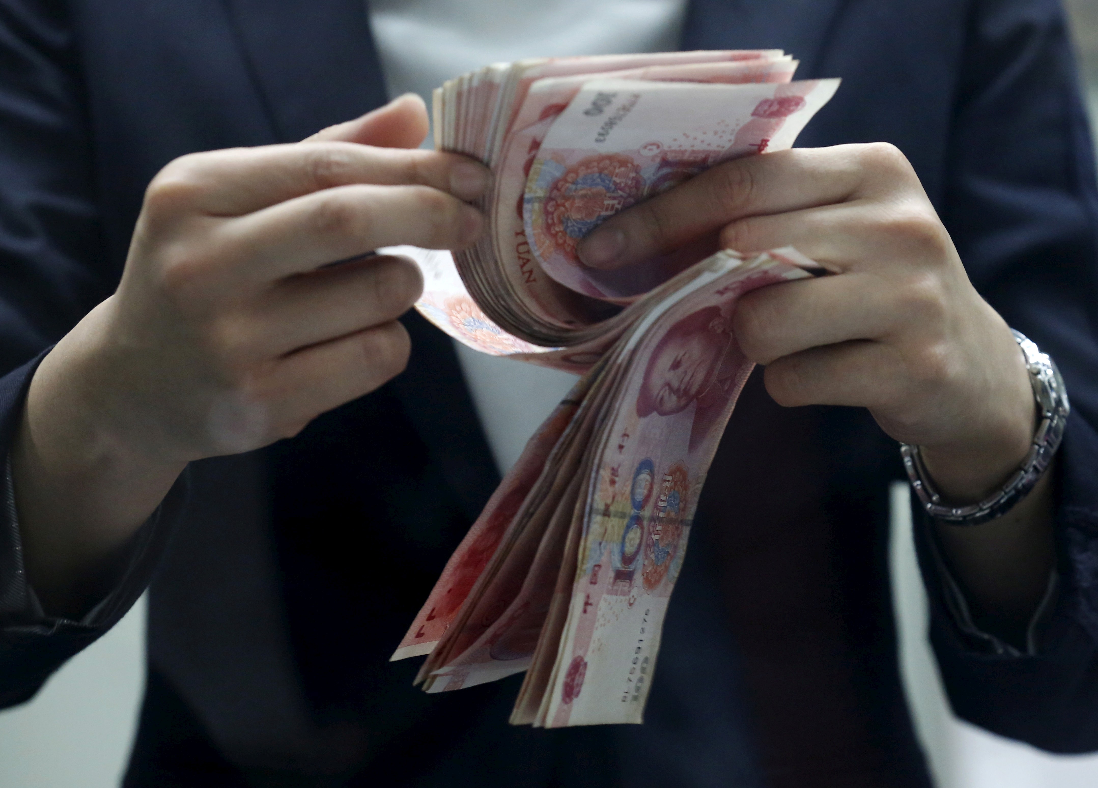A bank teller counts Chinese 100 yuan banknotes at a branch of a foreign bank in Beijing. Photo: Reuters