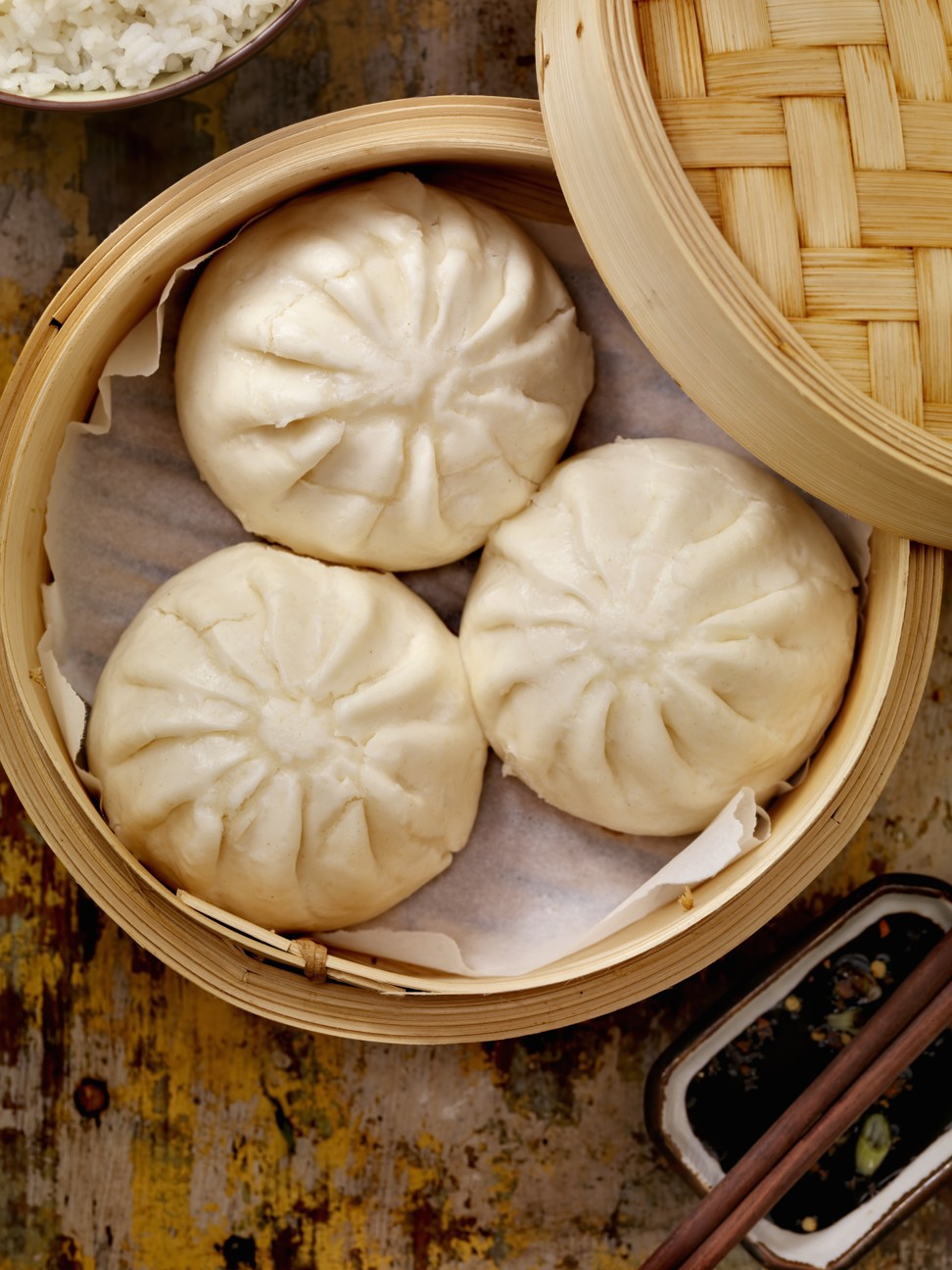 Steamed pork buns in a bamboo steamer with soy sauce and rice. But should you be ordering chicken instead? Photo: Getty Images