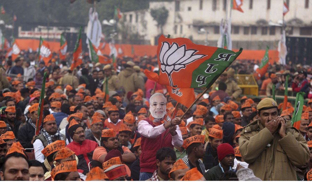 A man wearing a mask of Indian Prime Minister Narendra Modi waves the BJP flag during a rally in New Delhi. Photo: AP