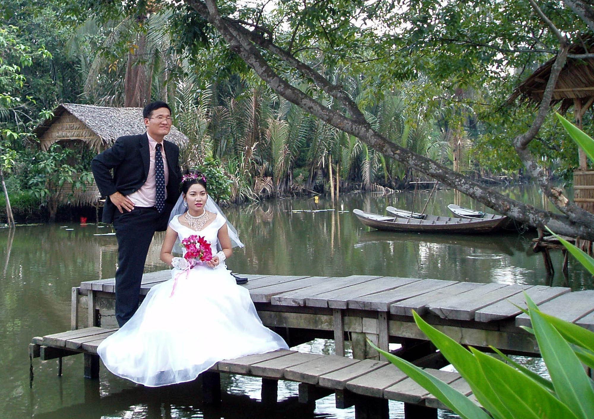 A South Korean man poses with his Vietnamese bride for their wedding photo at a park in Ho Chi Minh City, Vietnam. Photo: AP