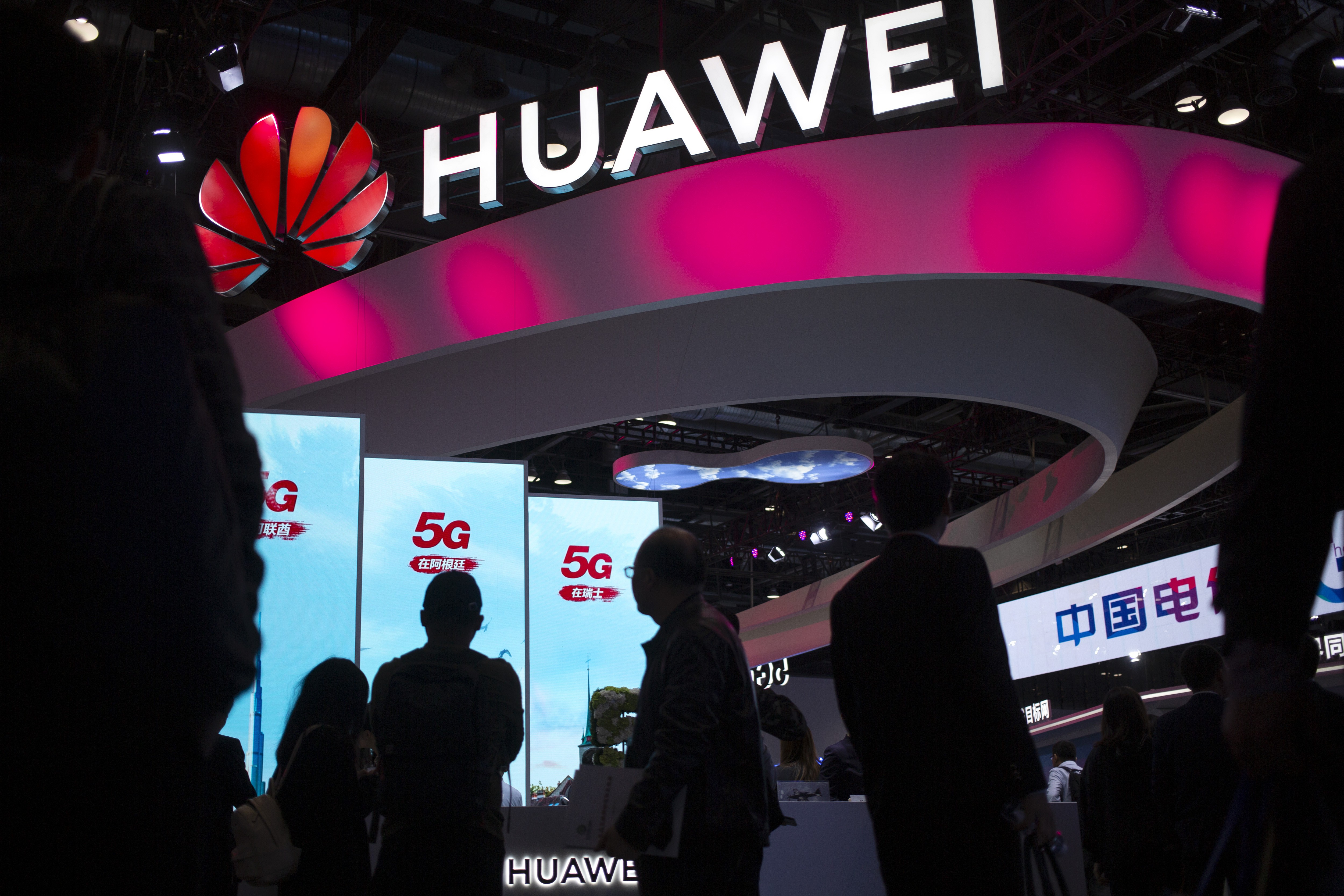 Attendees walk past a display for 5G services from Chinese telecoms firm Huawei at the PT Expo in Beijing. Photo: AP