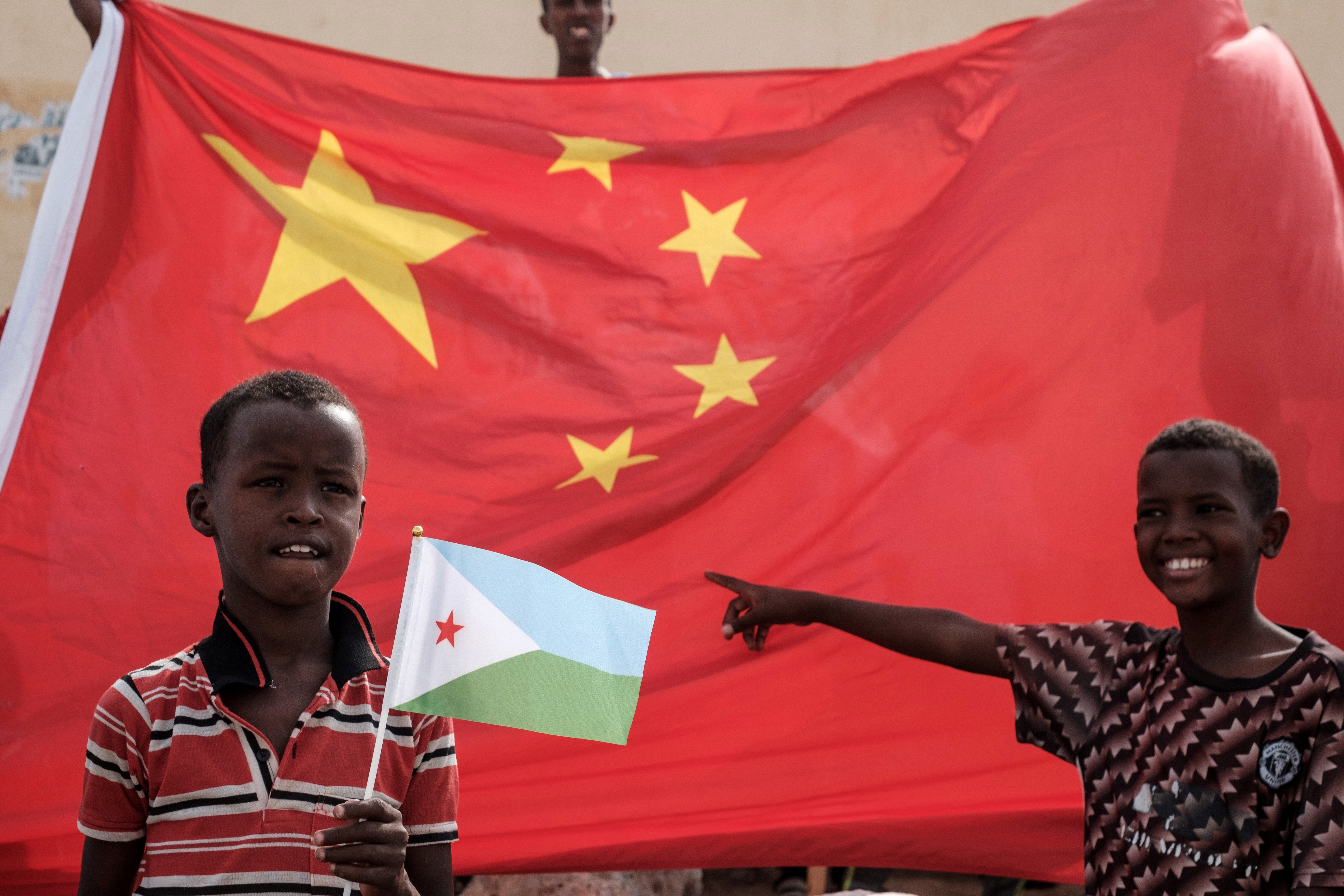 A boy holds Djiboutian national flag in front of Chinese national flag as he waits for Djibouti's President Ismail Omar Guellehas before the launching ceremony of new 1,000-unit housing construction project in Djibouti in 2018. Photo: AFP