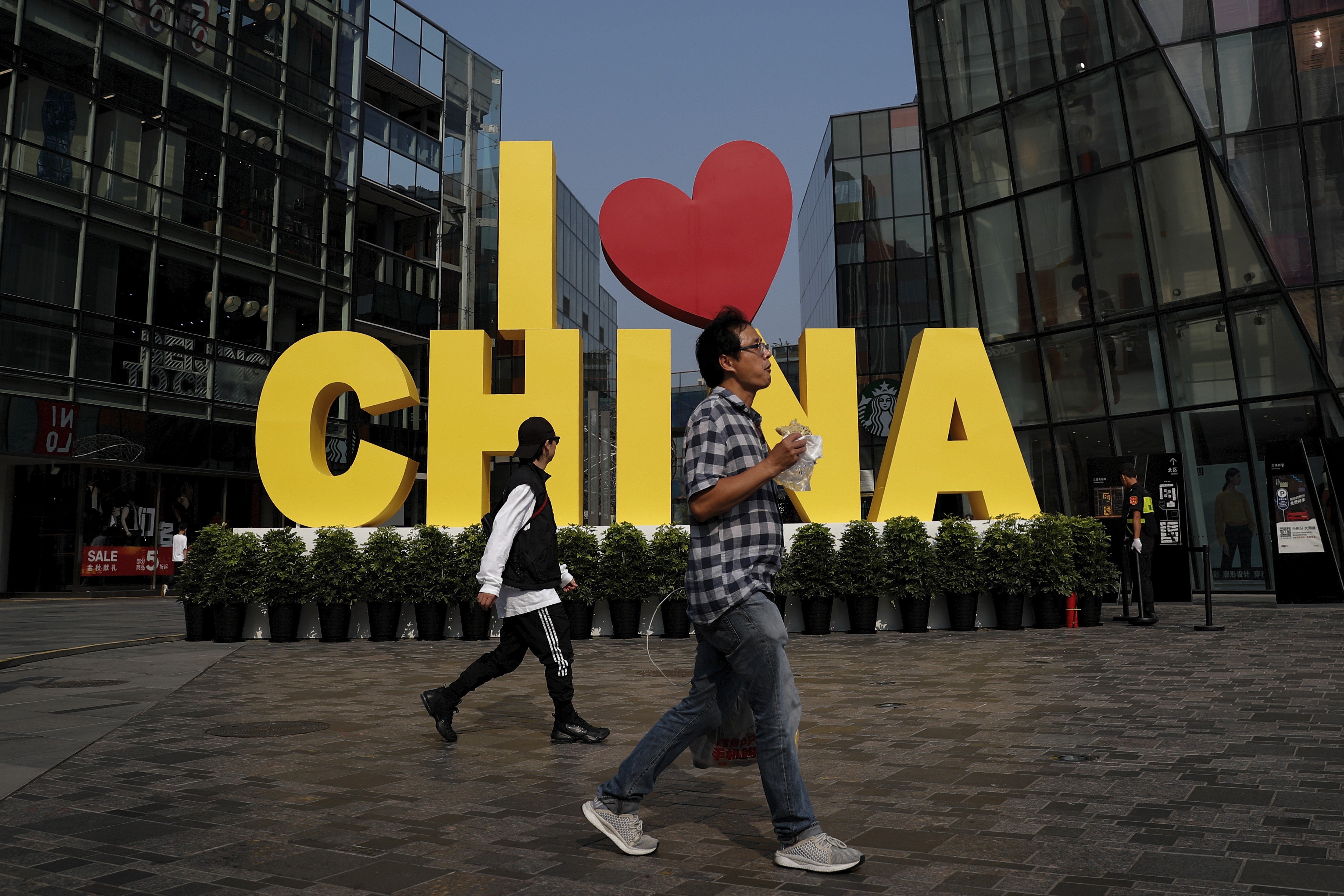 People walk past a shopping centre in Beijing on September 29. The government must step back from economic overreach to allow investor confidence to return and the most dynamic companies to thrive. Photo: AP