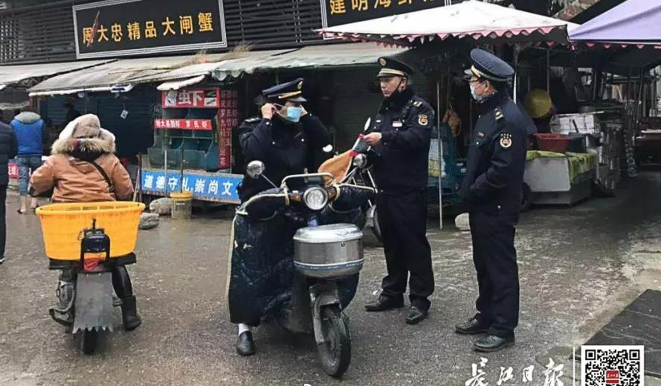 Law enforcement officers stand guard outside the market in Wuhan. Photo: Yangtze Daily