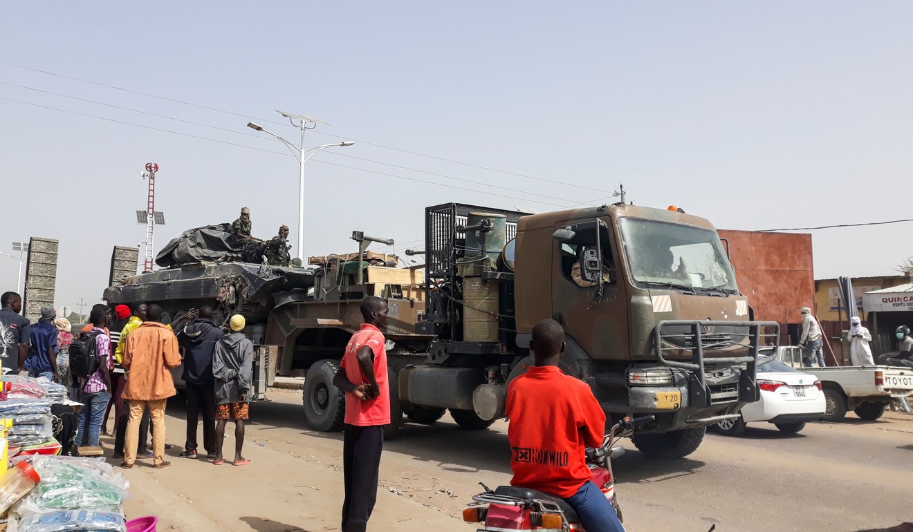 Pedestrians look on as a tank is transported on a truck in the streets of N’Djamena on January 3. Photo: AFP