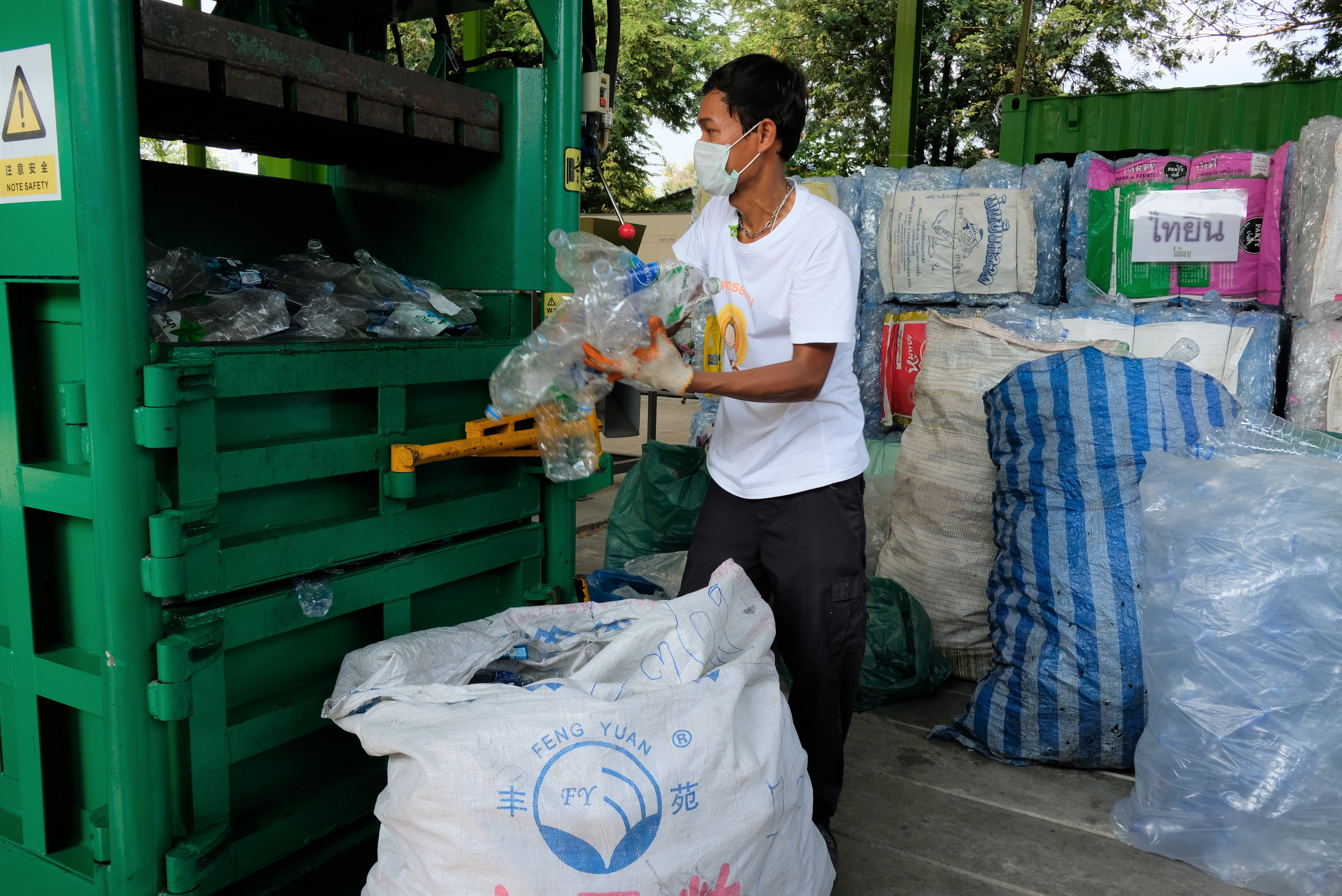 Plastic bottles donated to a Buddhist monastery in Thailand for recycling are fed into a machine that flattens them. Photo: Tibor Krausz