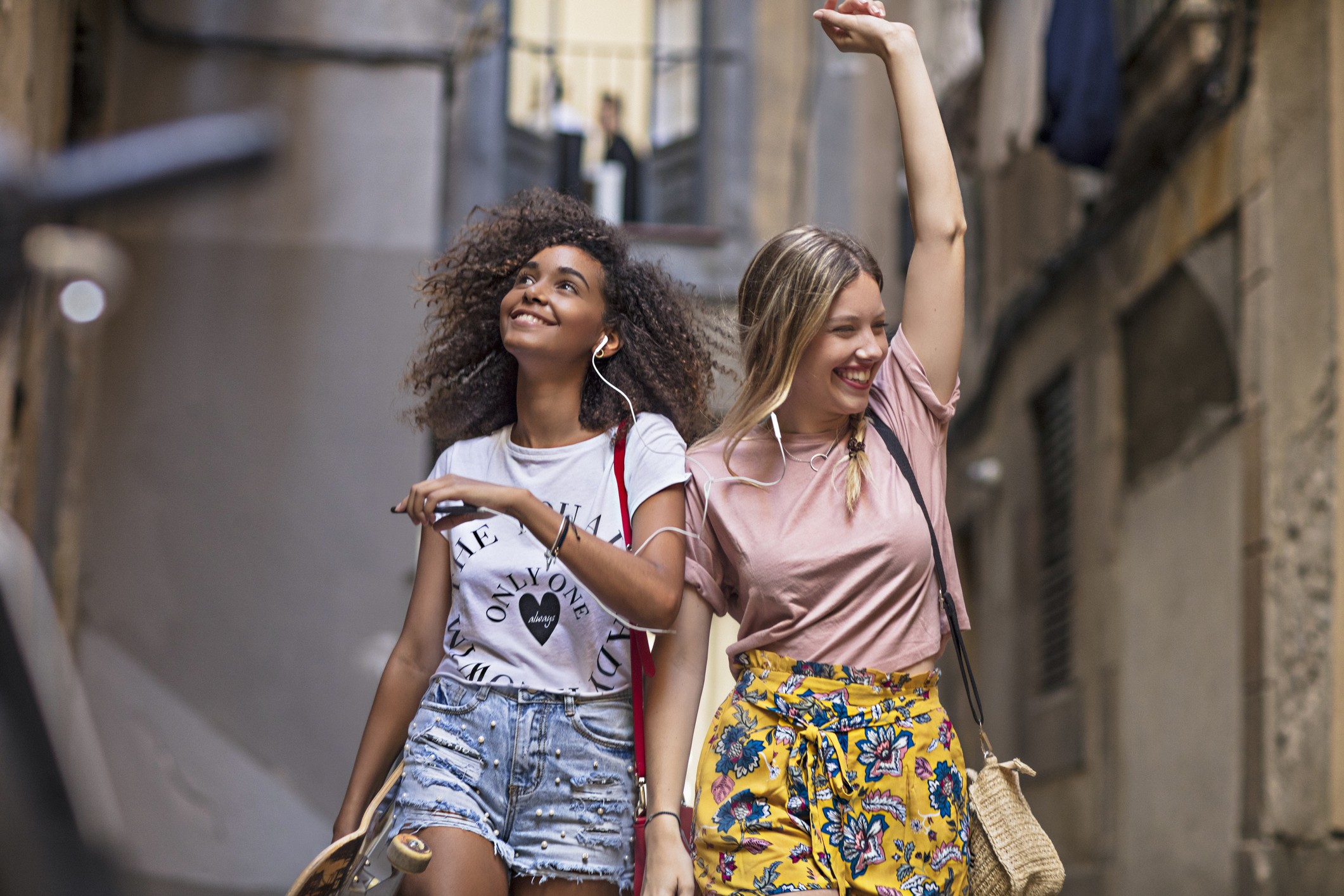 Two multi-ethnic young women friends having fun sharing music in the street. Photo: Getty Images