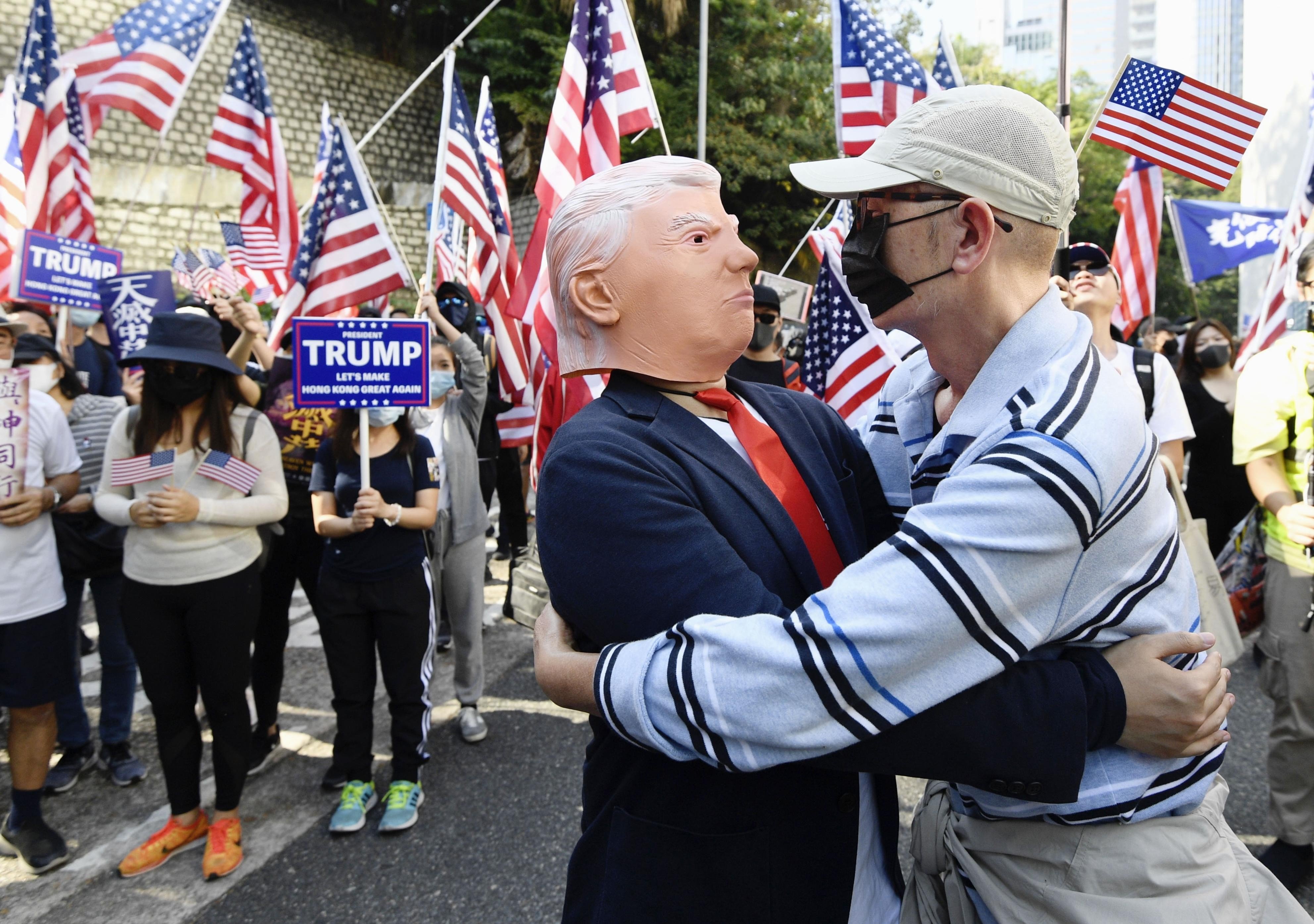 A masked protester embraces a man wearing a Donald Trump mask at a pro-US rally on December 1 in Hong Kong, after US President Donald Trump signed the Hong Kong Human Rights and Democracy Act. Photo: Kyodo