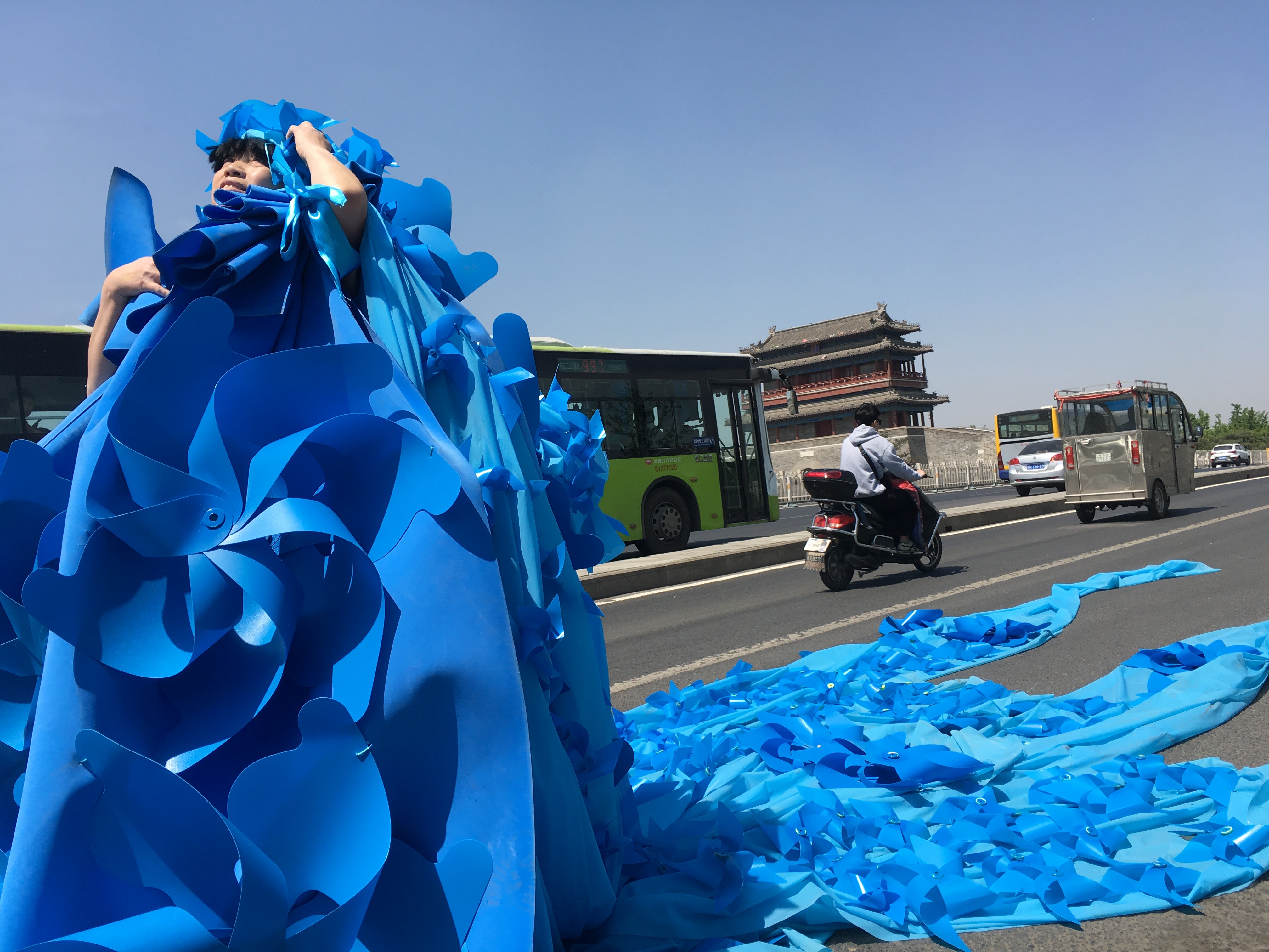 Kong Ning in a dress made of blue pinwheels in Beijing in 2017. She created this dress in the hope the wheels would blow the smog away.