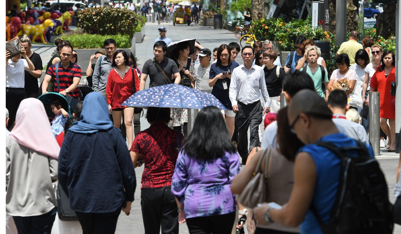 Pedestrians walk on the busy pavement in the Orchard Road shopping district in Singapore. Photo: AFP