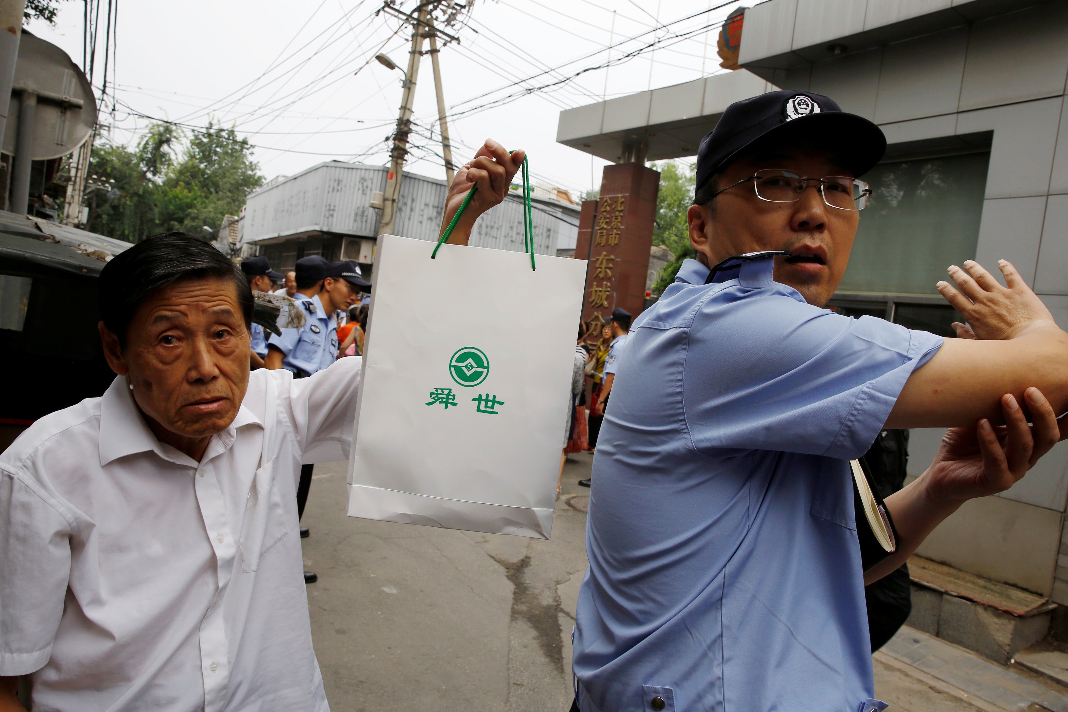 A man in Beijing holds up a bag with a logo of a P2P lender as he attends a protest over losses incurred in peer-to-peer (P2P) investment schemes. Photo: Reuters