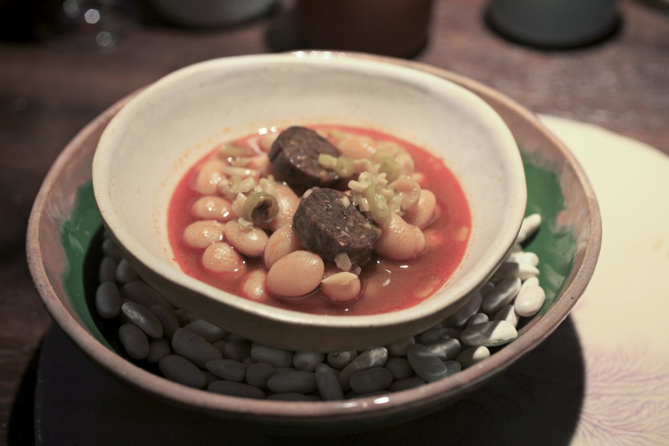 Stewed pochas white beans with rounds of “black sausage” made from eggplant and nuts. Photo: Jeff Koehler