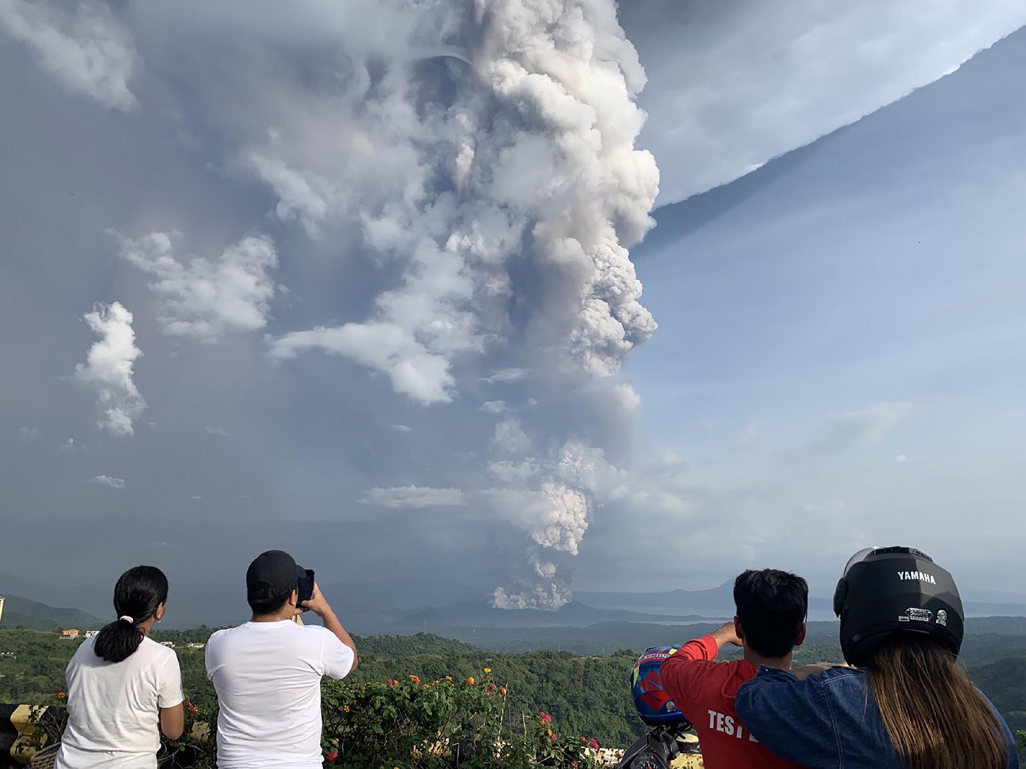 People take photos of a phreatic explosion from the Taal volcano, southwest of Manila in the Philippines. Photo: AFP