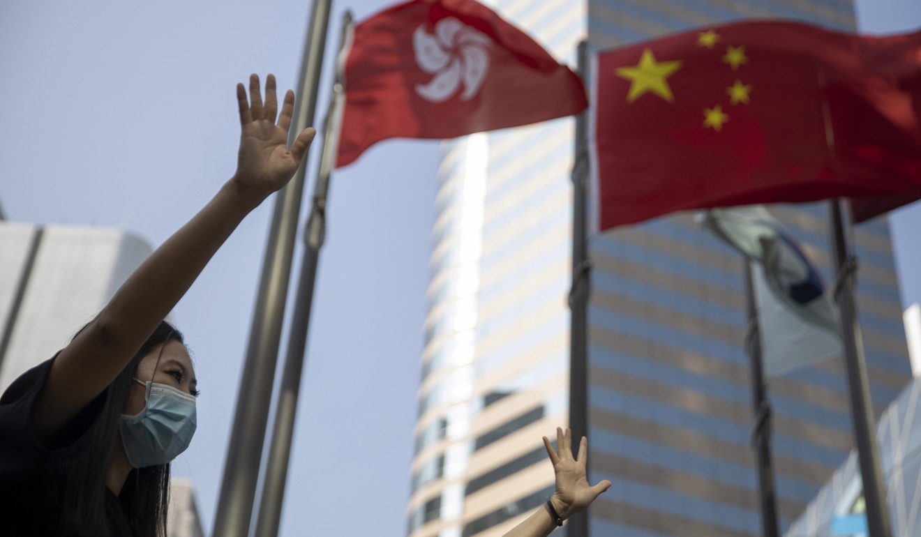 Protesters hold up their hands to represent their five demands at Exchange Square, as the Hong Kong and Chinese flags flutter behind them, on November 15. Photo: AP