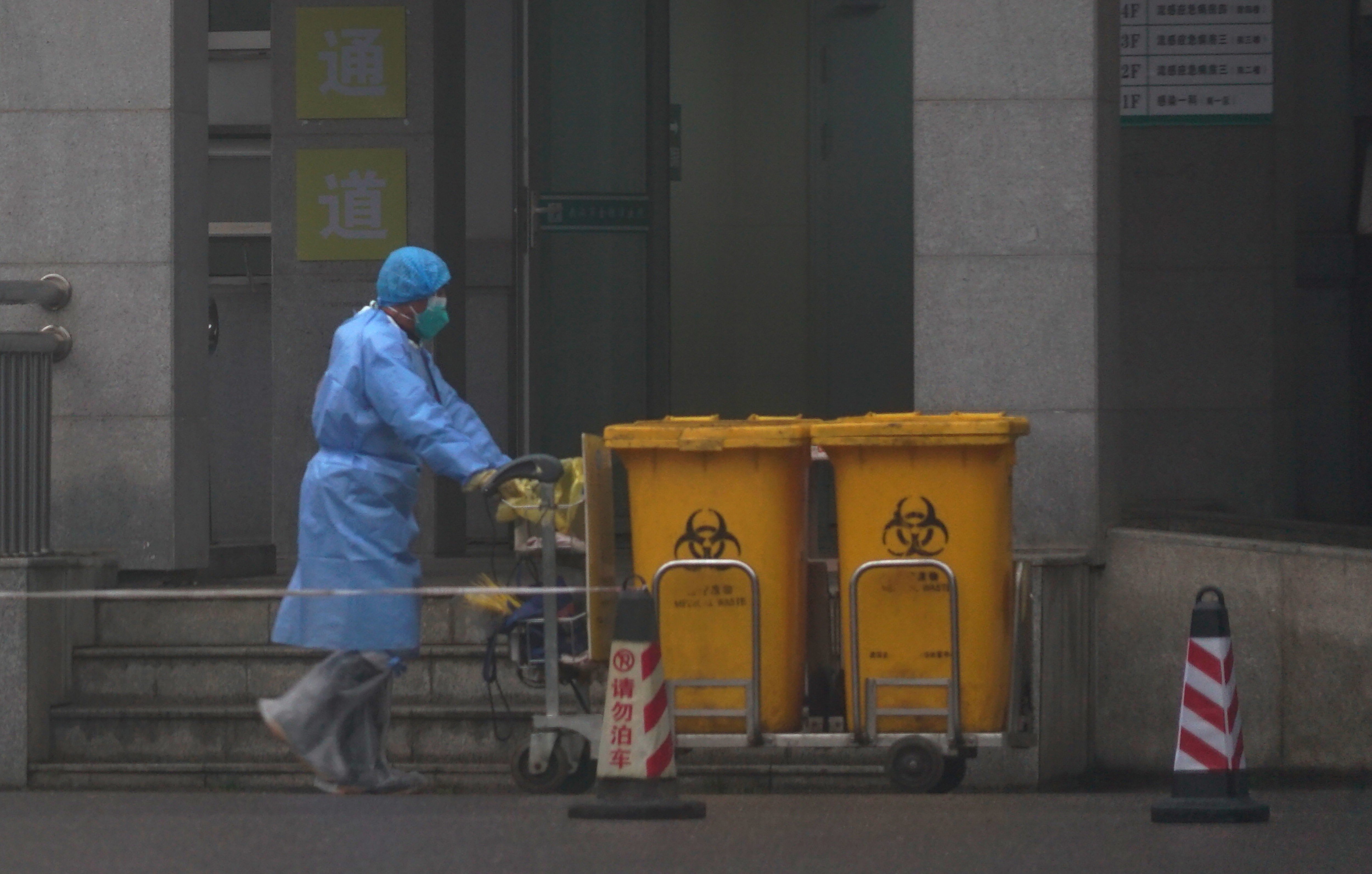 Staff move bio-waste containers past the entrance of the Wuhan Medical Treatment Centre in China, where some people infected with the new virus are being treated. Photo: AP