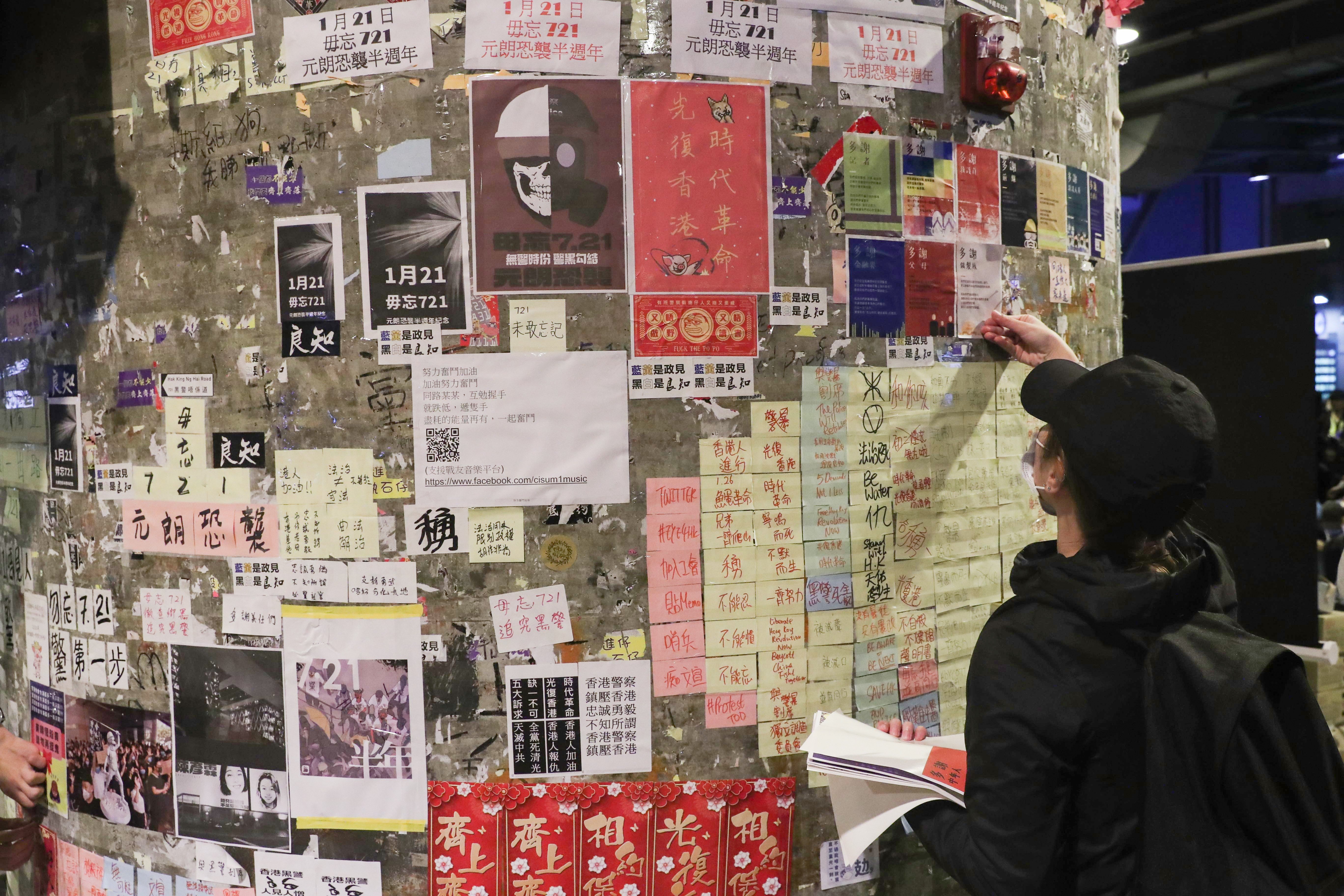 A protester adds to a wall of notes and posters related to the anti-government movement in Hong Kong, as hundreds of Hongkongers gathered near Yuen Long station on January 21 to mark the six-month anniversary of a mob attack on train passengers. Photo: Sam Tsang