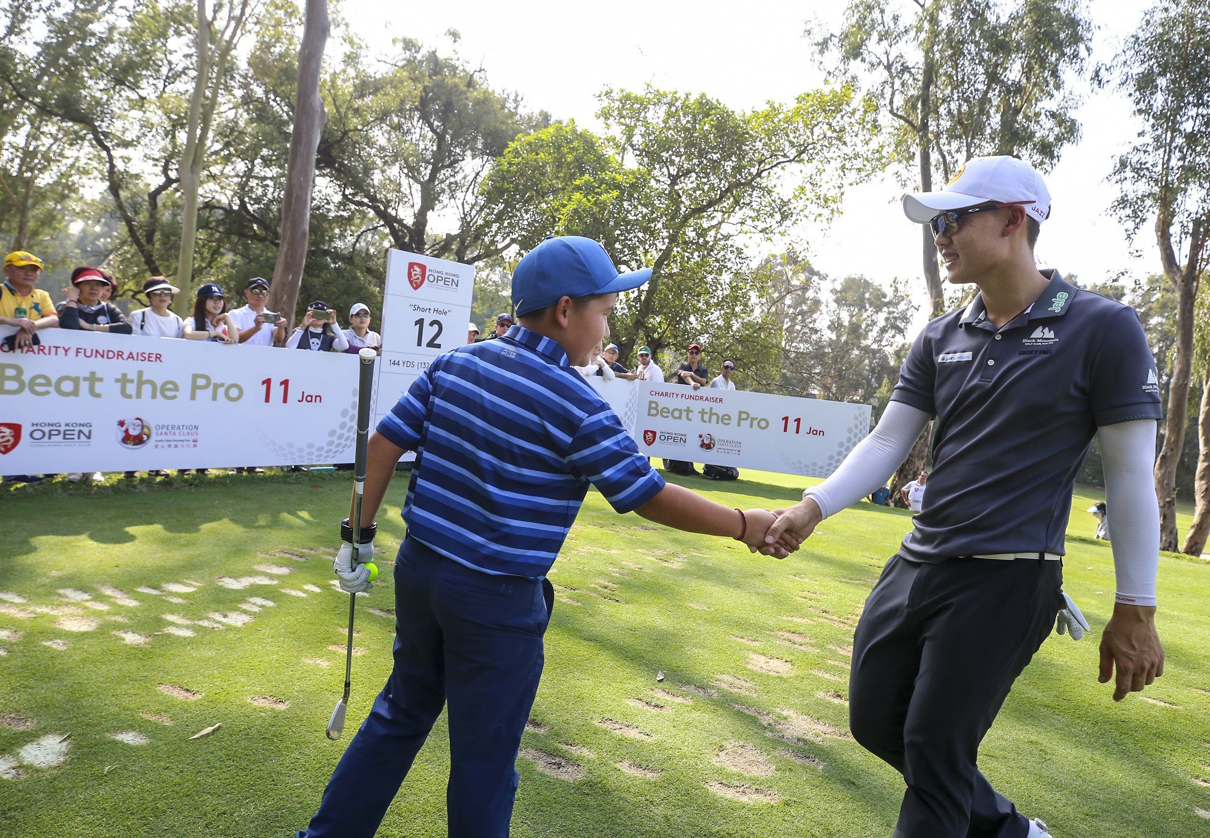 Jazz Janewattananond, of Thailand, shakes hands with a young golfer taking part in the Beat the Pro competition during the Hong Kong Open. Photo: Dickson Lee