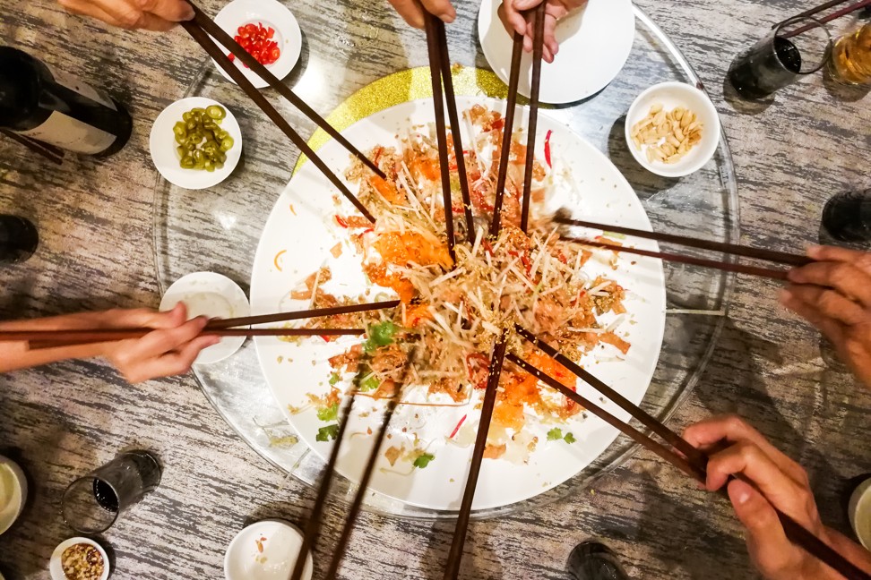 People tossing yee sang or yusheng during Chinese New Year , traditional practice in Malaysia and Singapore for luck and prosperity