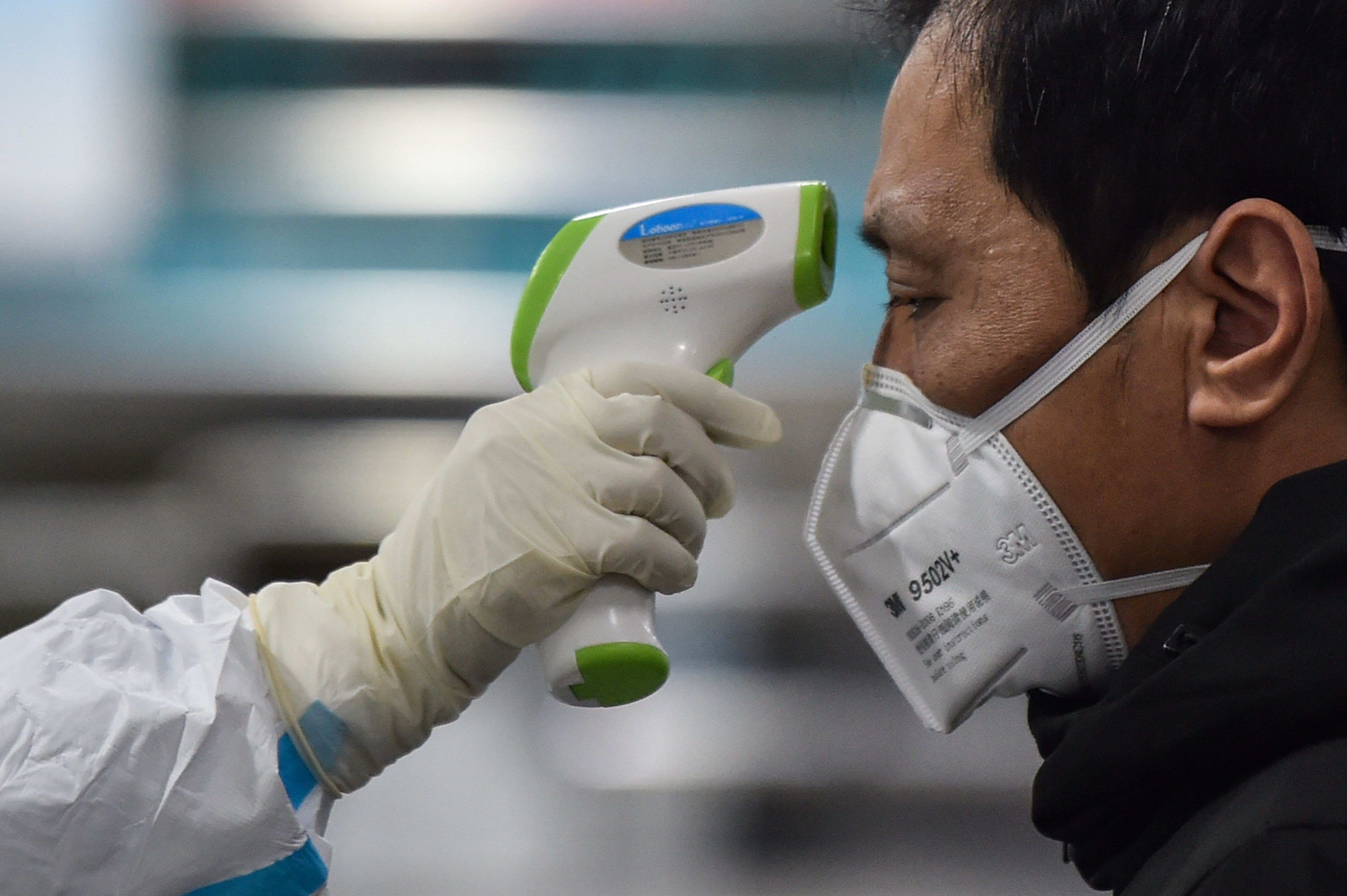 A medical worker checks the temperature of a Wuhan resident as scientists rush to develop a vaccine for the coronavirus in China. Photo: AFP