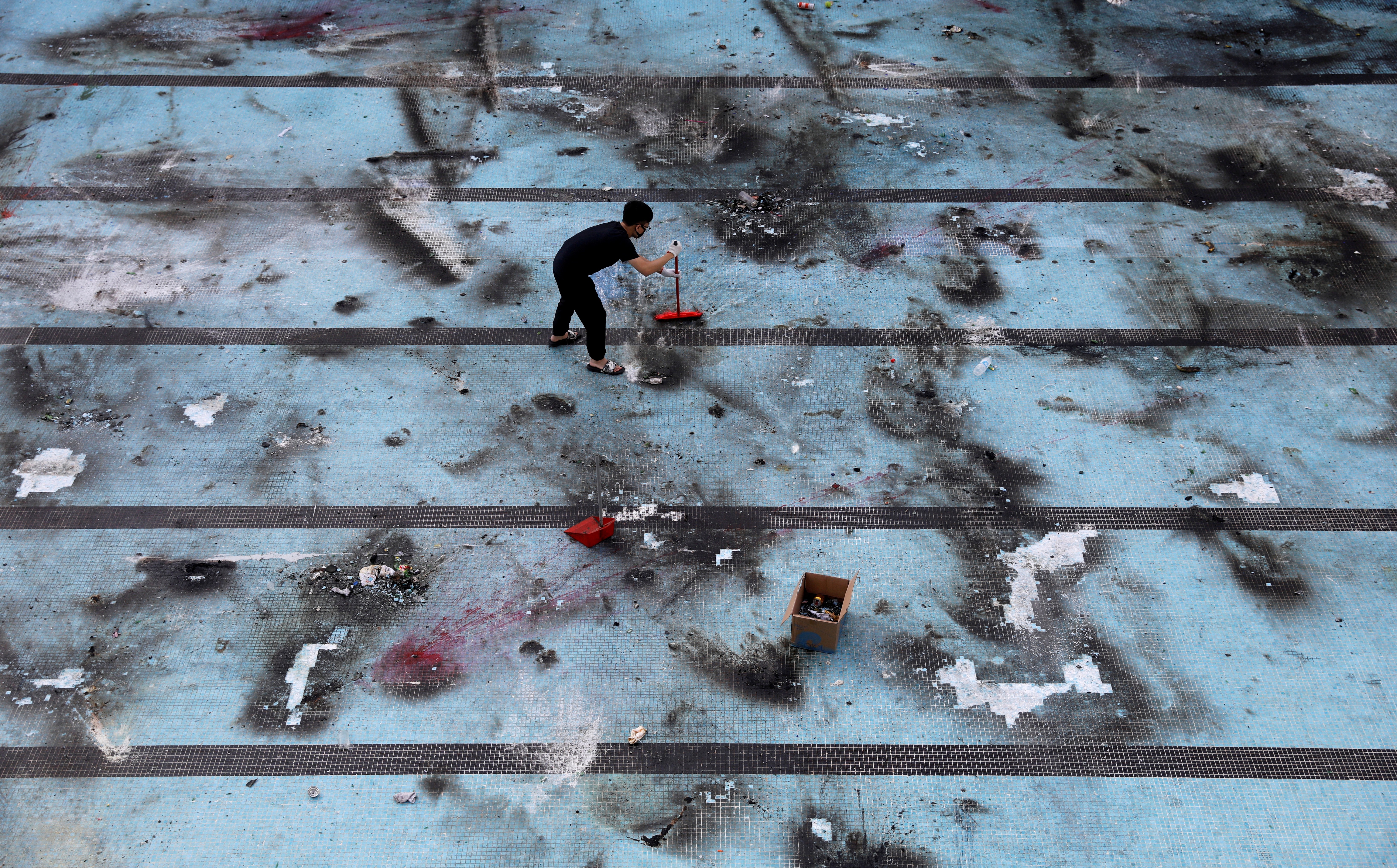 An anti-government protester cleans up after protests at Polytechnic University in Hong Kong on November 16, 2019. Photo: Reuters