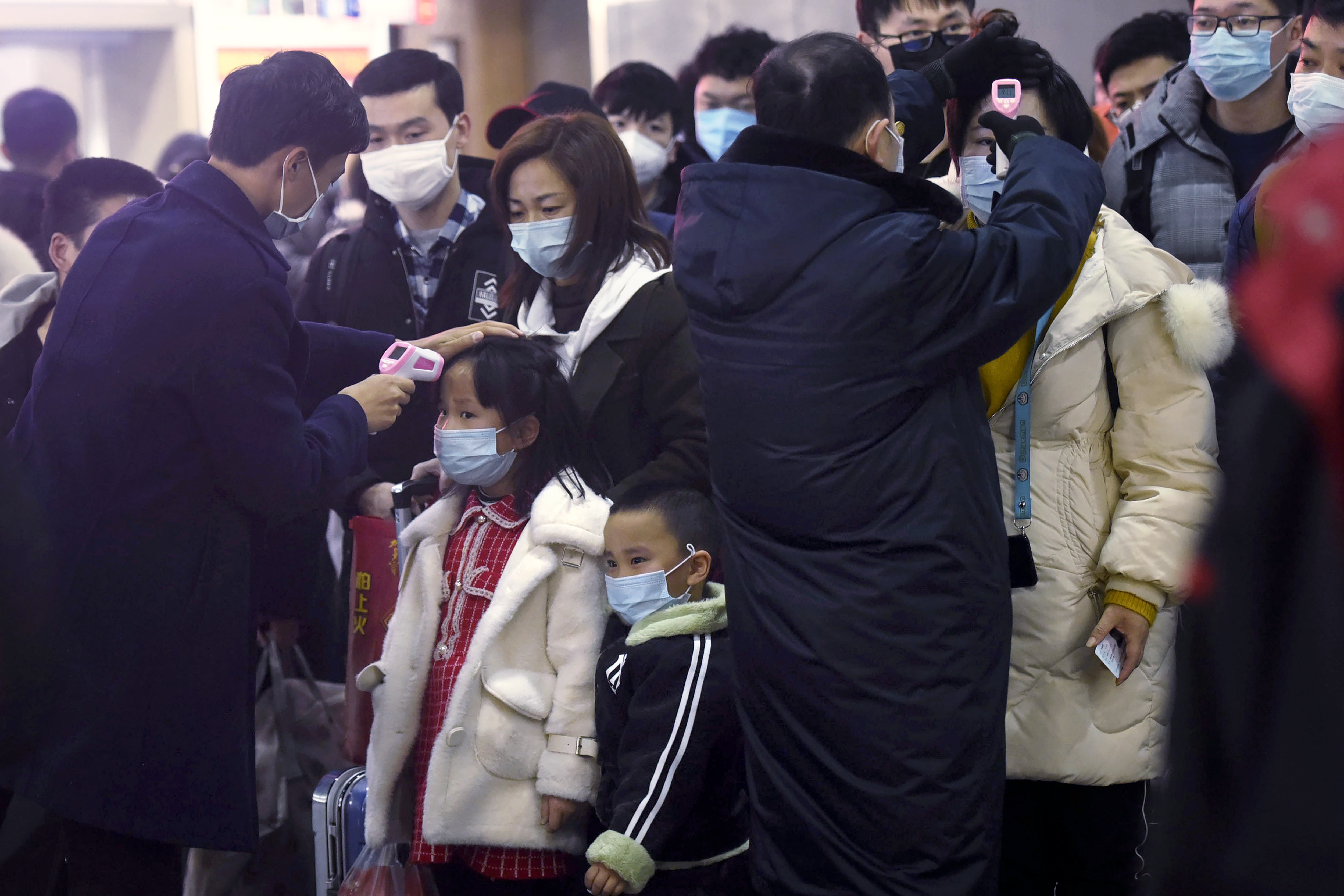 Workers use infrared thermometers to check the temperature of passengers arriving from Wuhan at a train station in Hangzhou in eastern China's Zhejiang Province, Thursday, Jan. 23, 2020. Photo: Chinatopix via AP