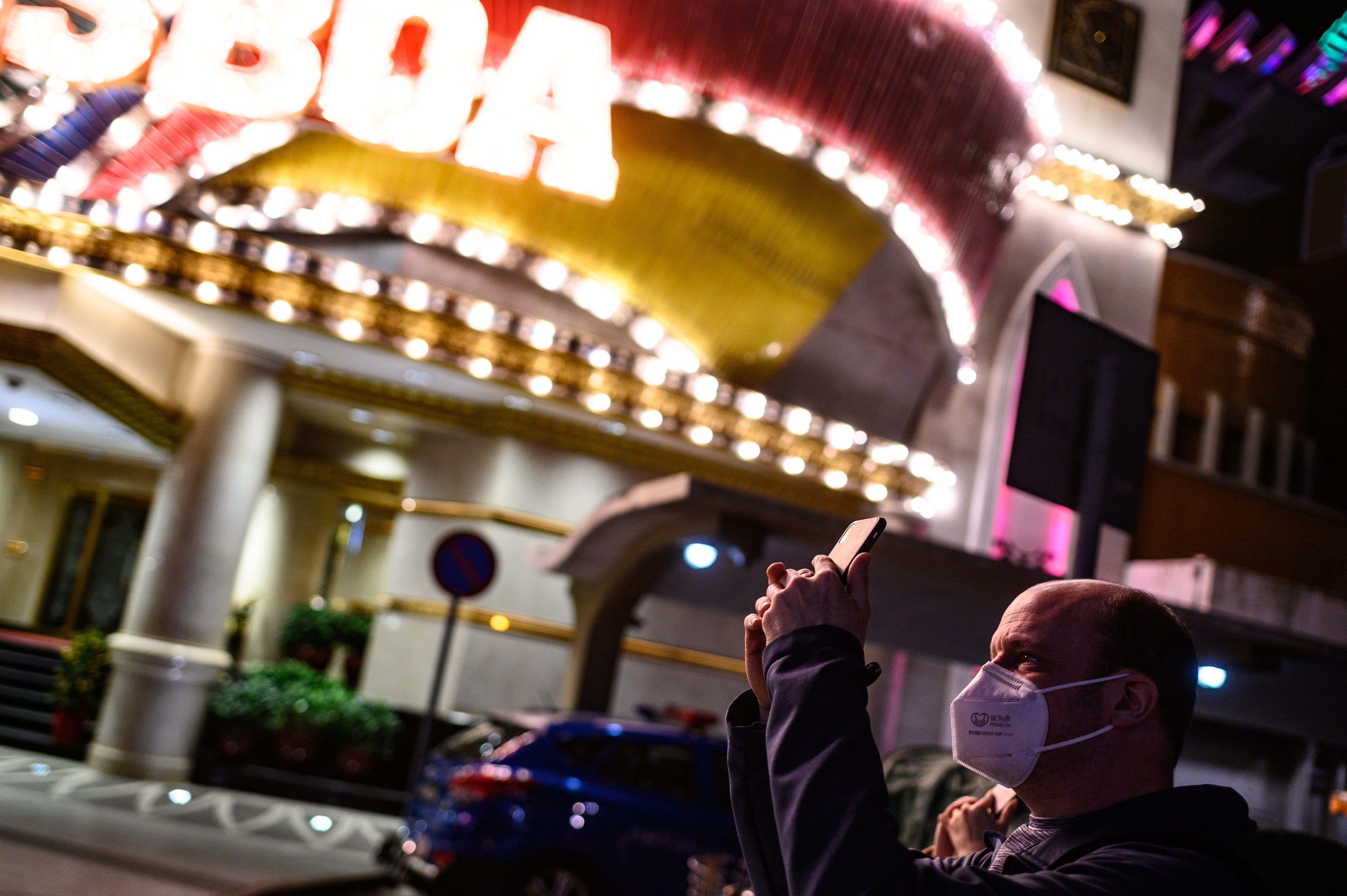 A man wears a face mask as he takes pictures outside a casino in Macau. Photo: AFP