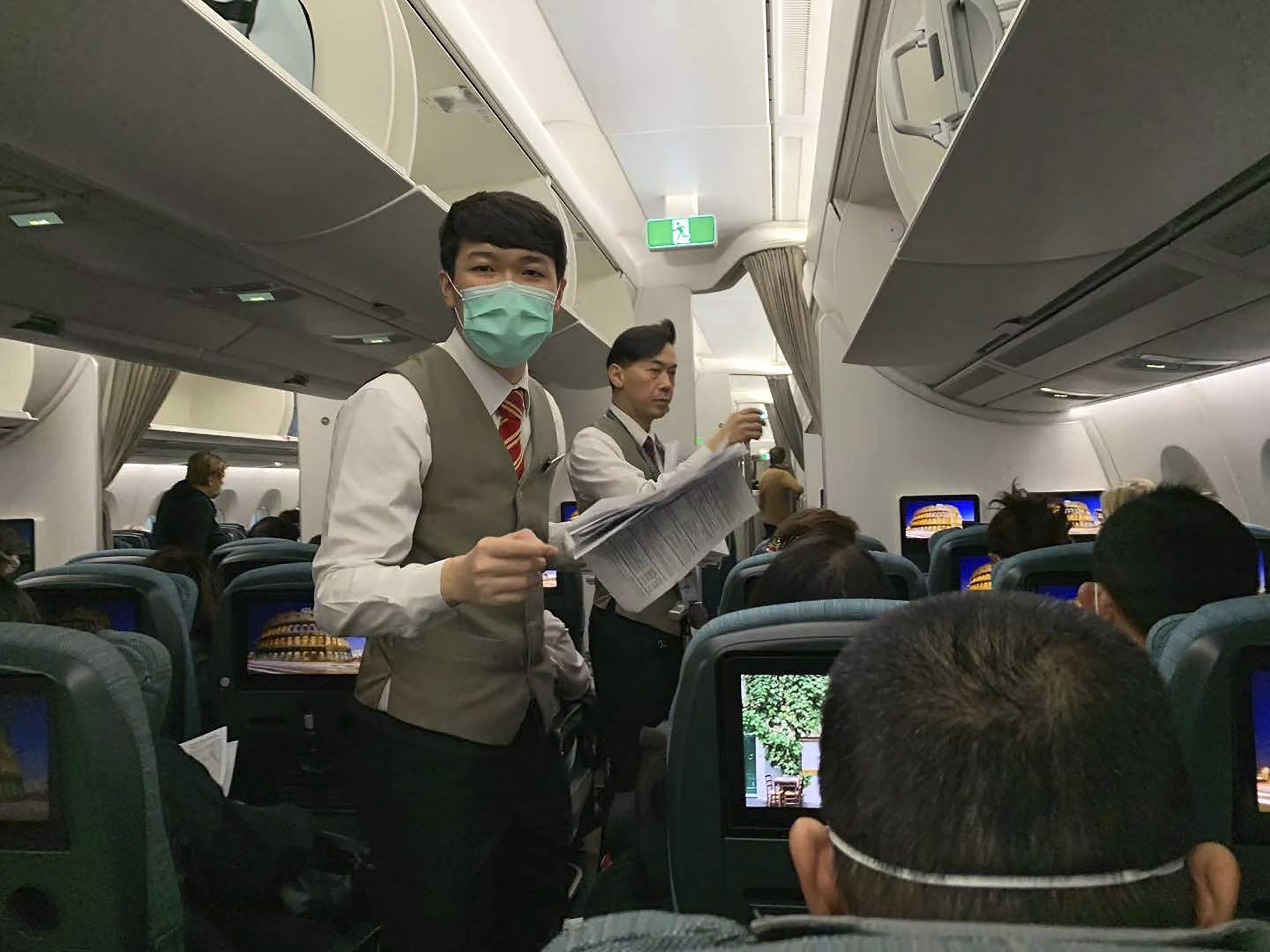 Flight attendants pass out health forms to passengers on a Cathay Pacific flight from Hong Kong to Rome on January 31. Photo: AP