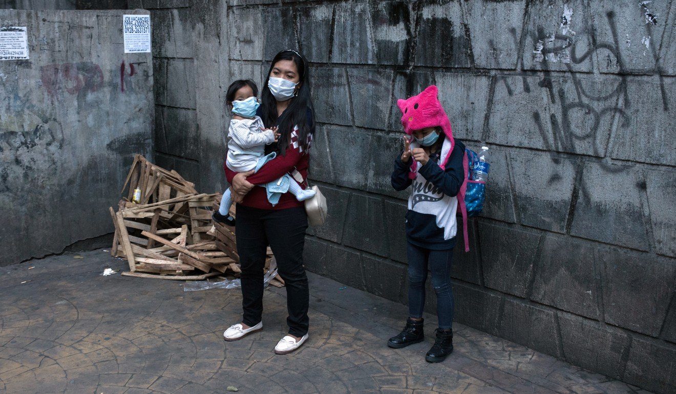 People wearing protective face masks stand on a pavement in Manila. Photo: Bloomberg