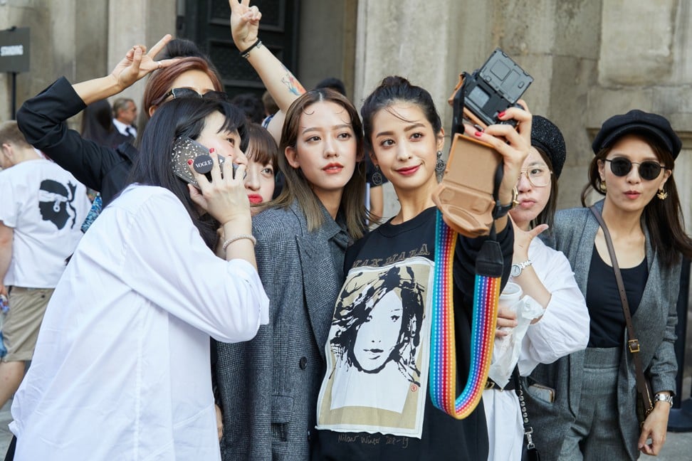 Asian women take selfies before the Max Mara fashion show at Milan Fashion Week’s street style event. Photo: Shutterstock