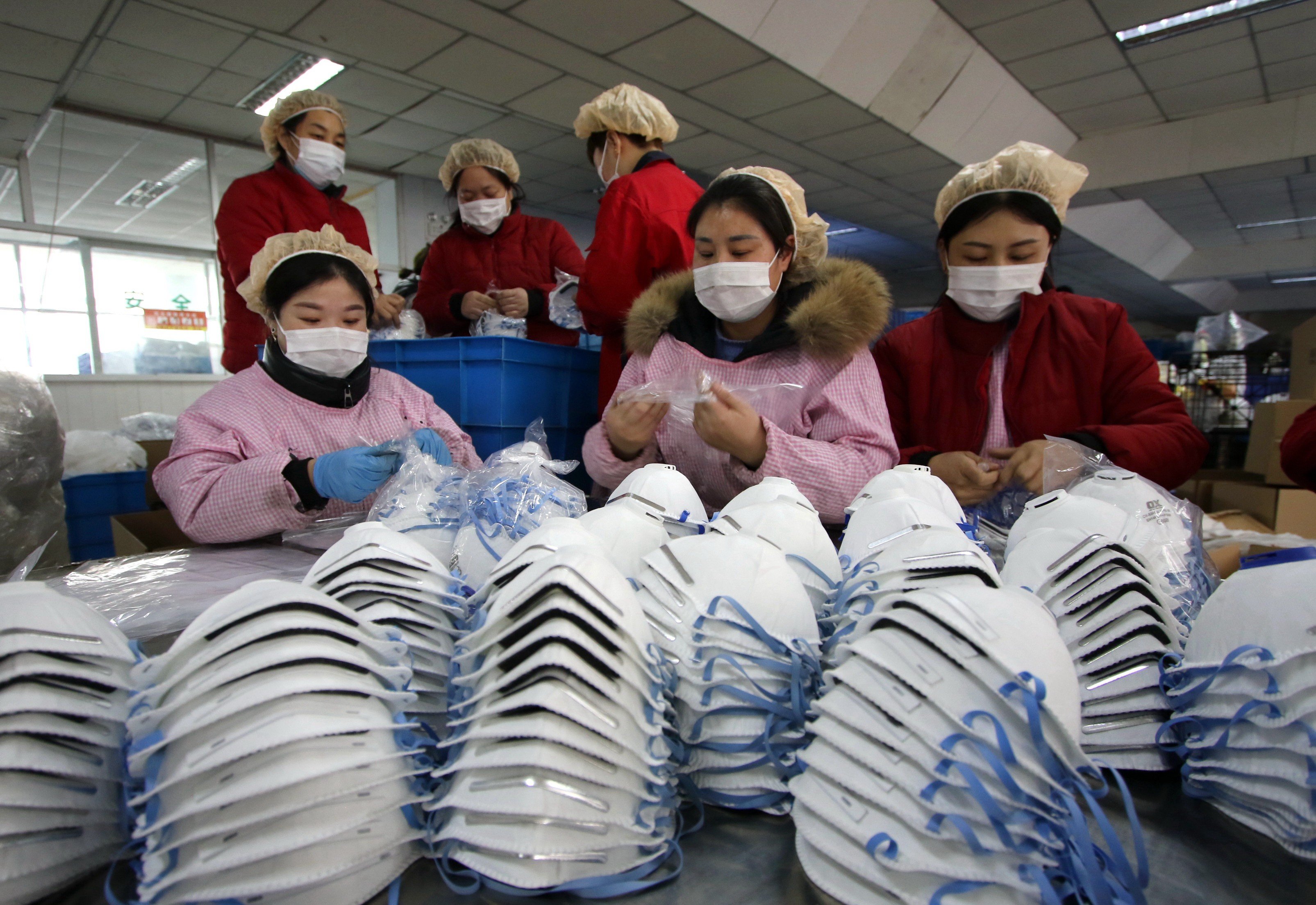 Workers manufacture protective face masks at a factory in Hebei Province. Photo: EPA-EFE