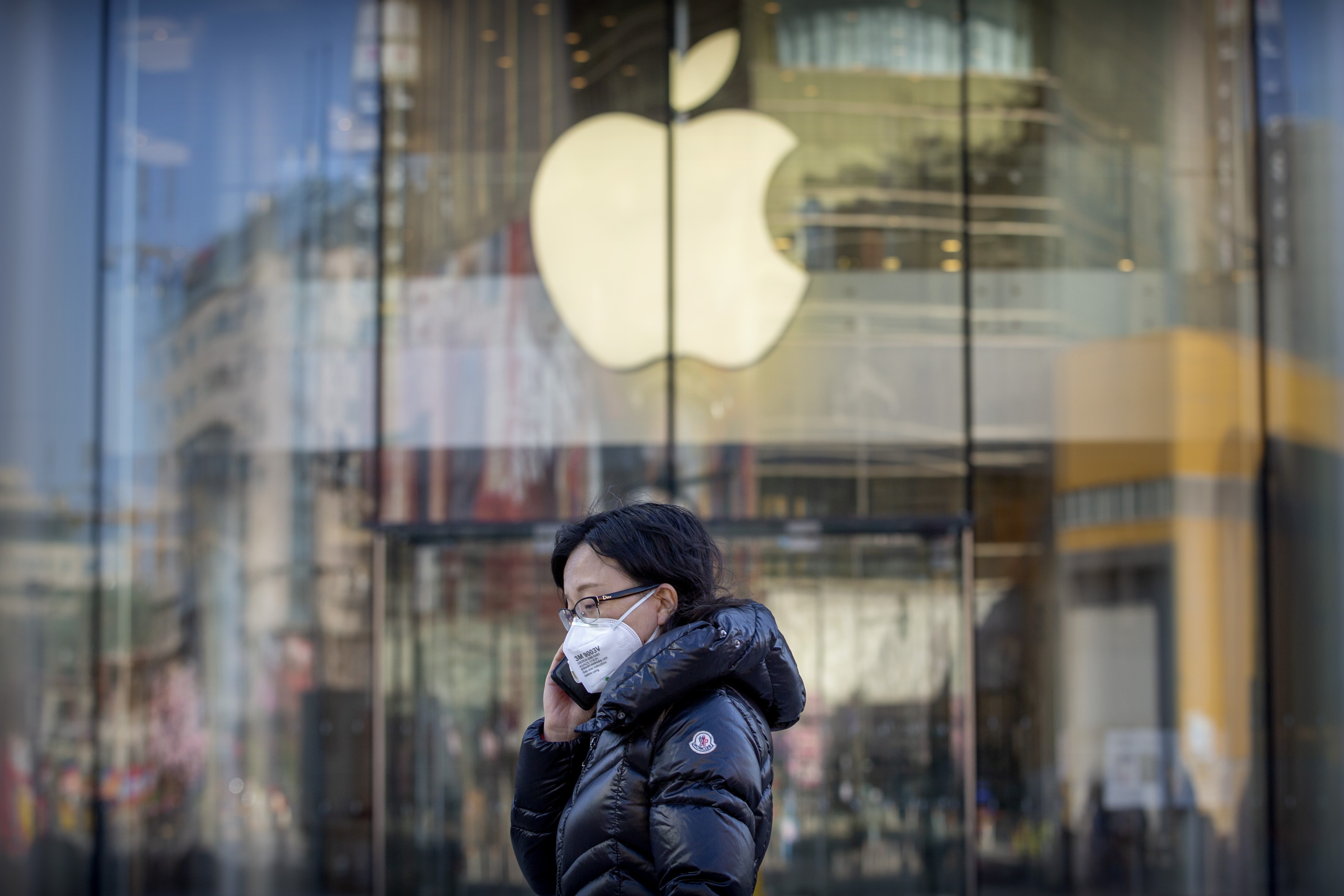 A woman wears a face mask as she walks past an Apple store in Beijing, China, that is temporarily closed due to coronavirus health concerns. Photo: AP