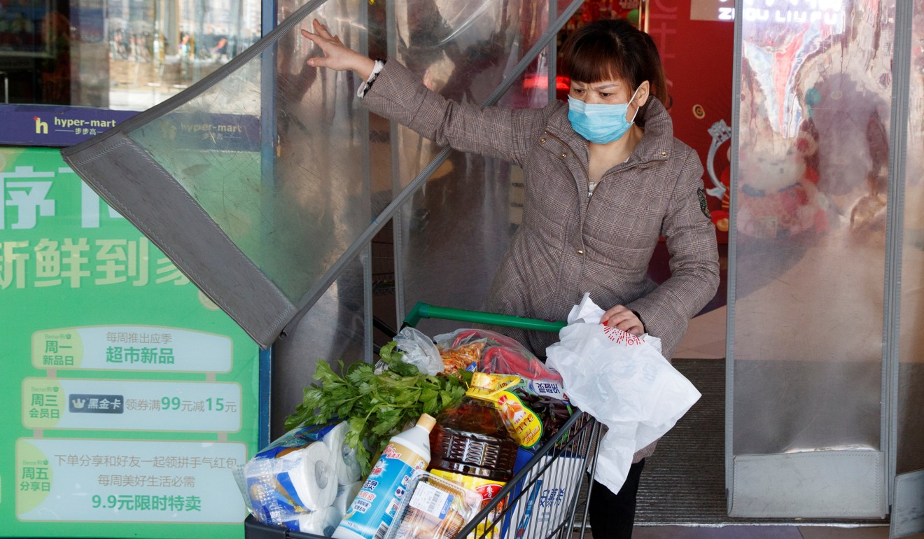 A woman wearing a face mask leaves a supermarket with a loaded shopping trolley in Changsha in China’s Hunan province on January 29. China’s market regulator has vowed to punish businesses engaging in price-gouging. Photo: Reuters