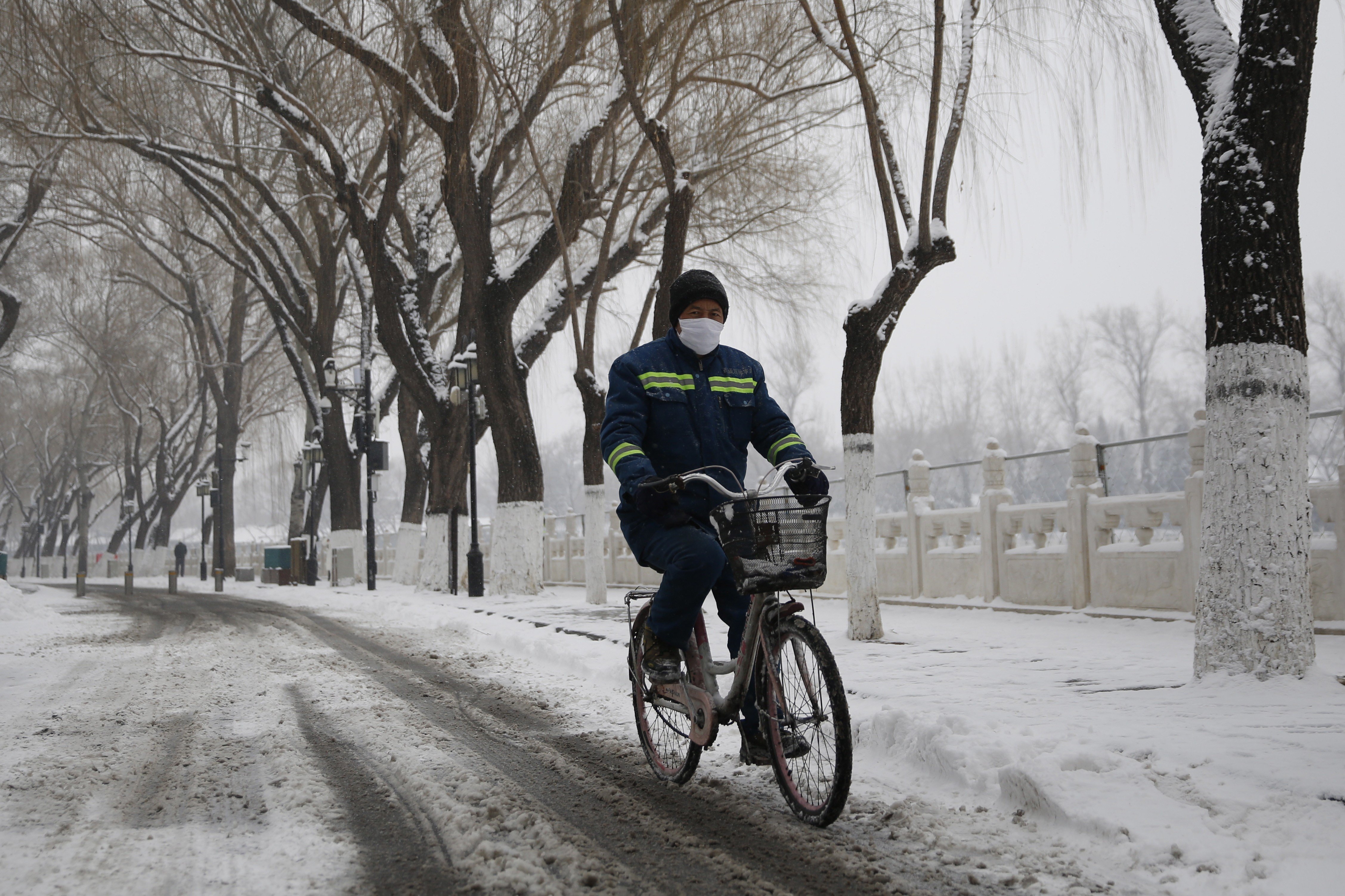 A Beijing cyclist wears a mask during a snowfall in the city on Thursday. Photo: EPA-EFE