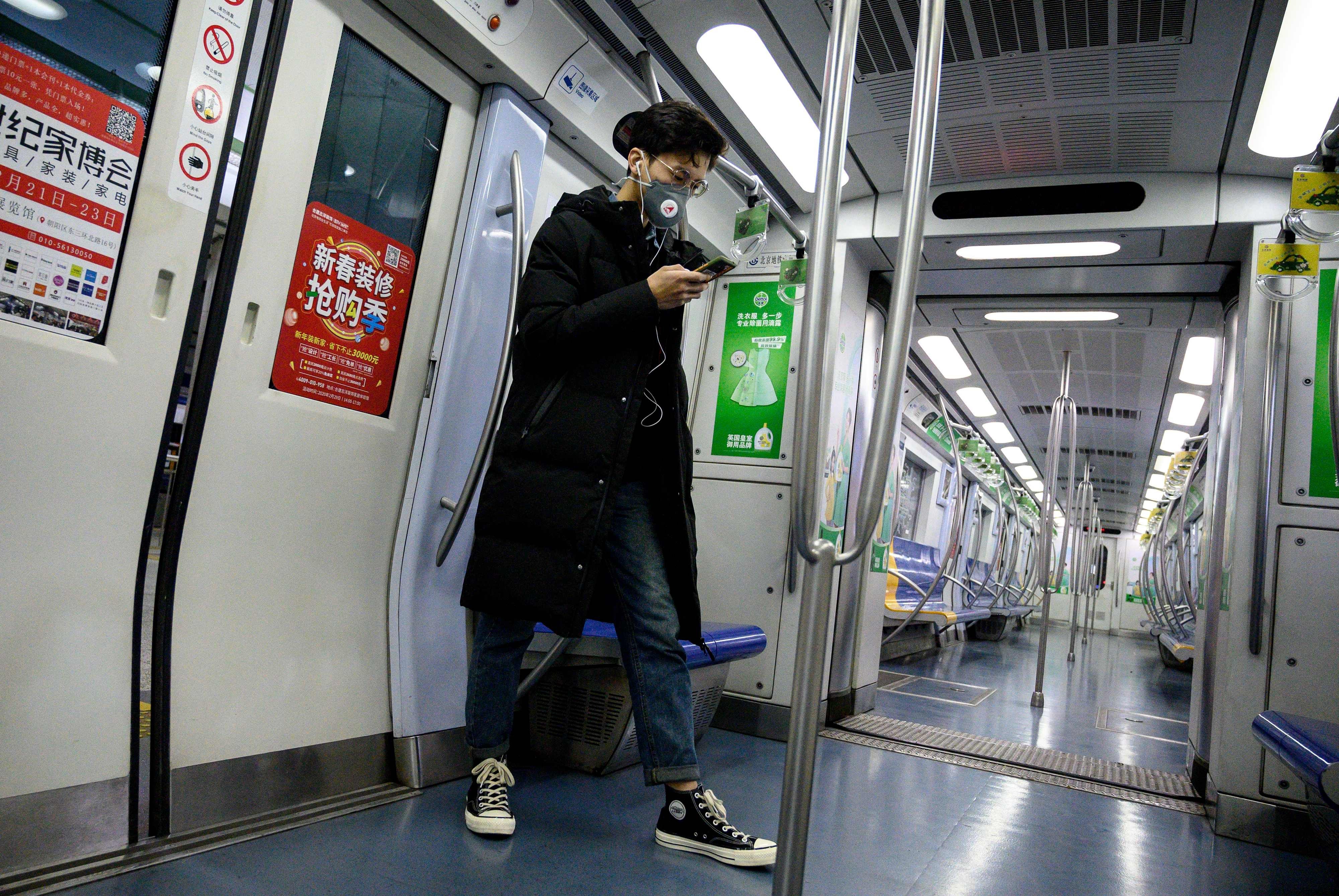A man wearing a protective face mask to help stop the spread of a deadly SARS-like virus which originated in the central city of Wuhan uses his mobile phone inside a train in Beijing on January 28, 2020. Photo: AFP