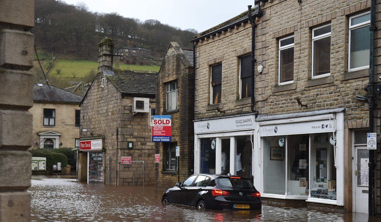 A car is seen submerged in floodwater in the streets of Hebden Bridge, northern England. Photo: AFP