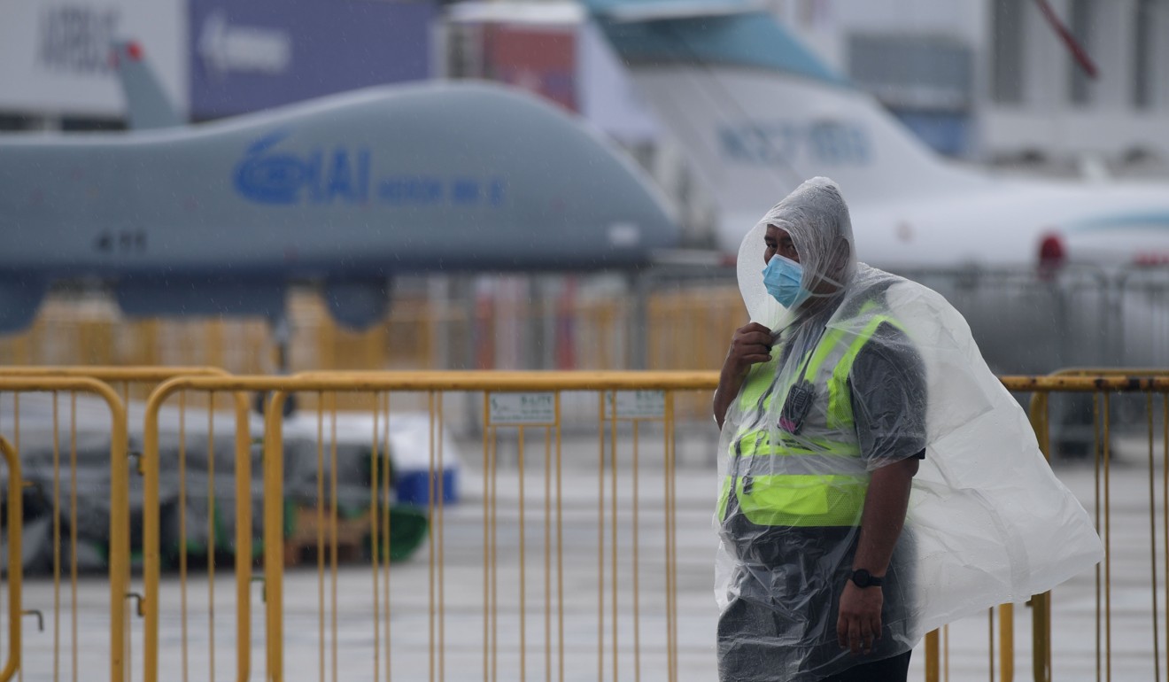 A member of staff wearing a protective face mask and plastic poncho is pictured on a road next to the tarmac during a media preview day ahead of the Singapore Airshow. Photo: AFP