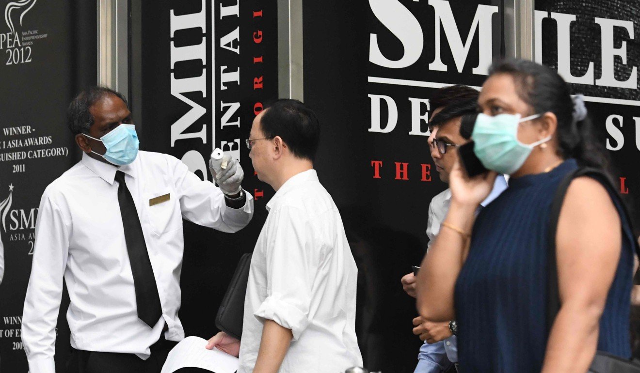 Building management staff screen visitors and tenants of a building in the financial district of Singapore. Photo: AFP