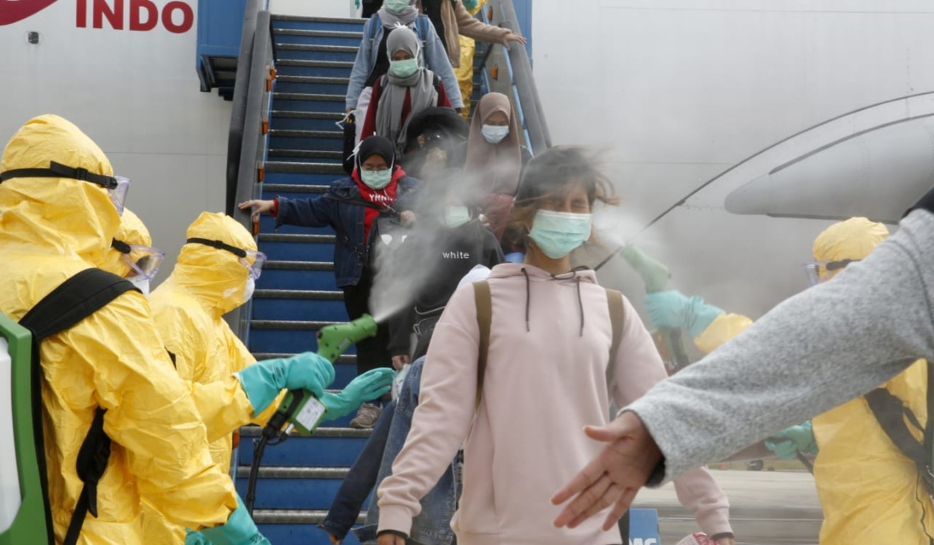 Medical officers spray evacuated Indonesian nationals with antiseptic after they arrive from Wuhan on February 2, 2020. Photo: Antara Foto via Reuters