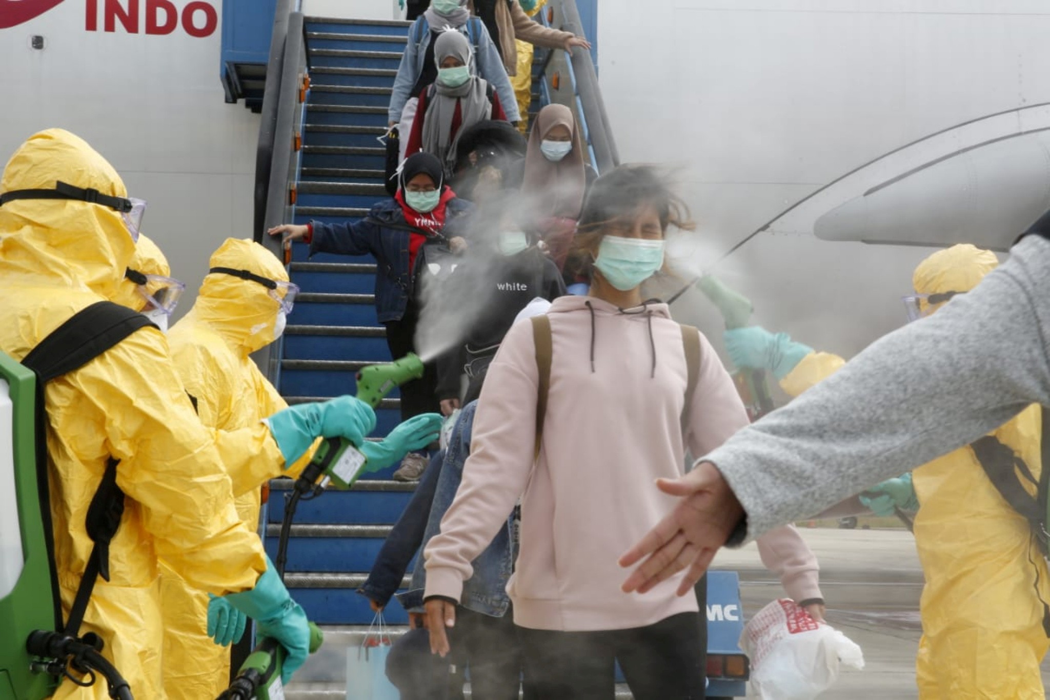 Medical officers spray evacuated Indonesian nationals with antiseptic after they arrive back from Wuhan on February 2, 2020. Photo: Antara Foto via Reuters