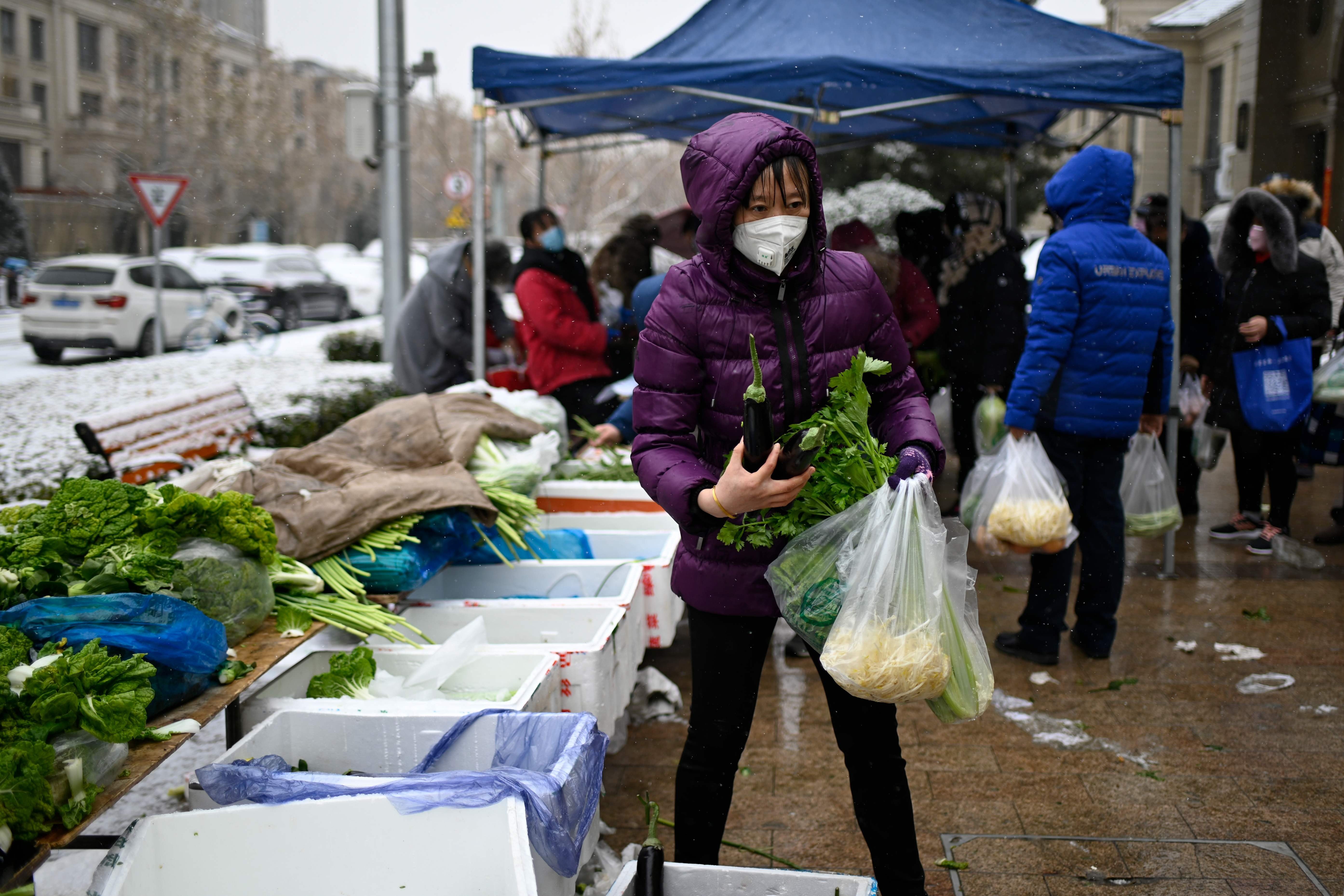 A woman wearing a mask buys vegetables at an open market in Beijing on February 2, after an outbreak of virus similar to the SARS pathogen. Photo: AFP