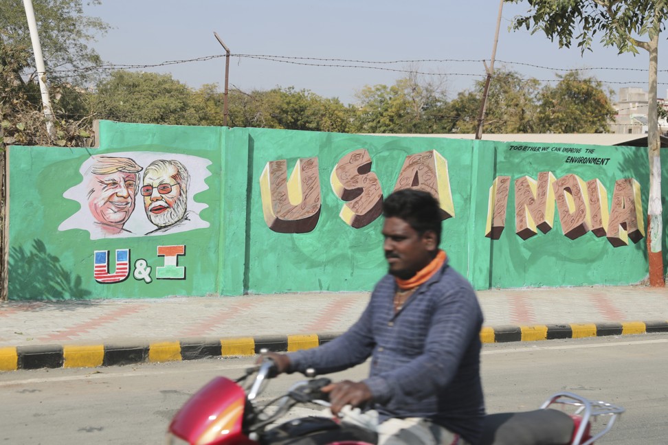 A man rides past a wall painted with portraits of US President Donald Trump and Indian Prime Minister Narendra Modi ahead of Trump’s visit in Ahmadabad on February 18, 2020. Photo: AP