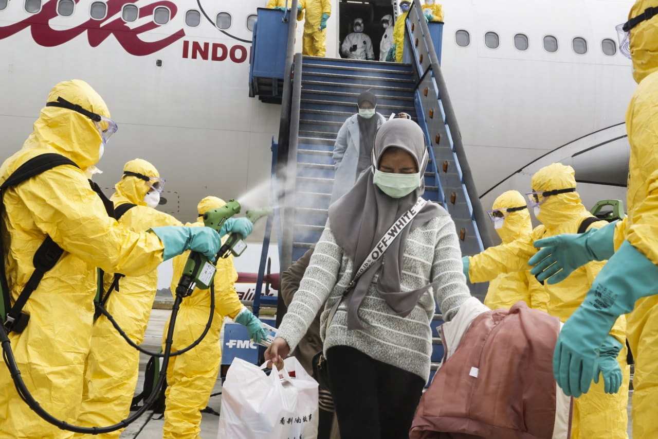 Indonesian nationals evacuated from Wuhan being sprayed with antiseptic as they arrive at Hang Nadim Airport. The 245 evacuees were transported on Natuna, Riau Islands, shortly after landing. Photo: EPA